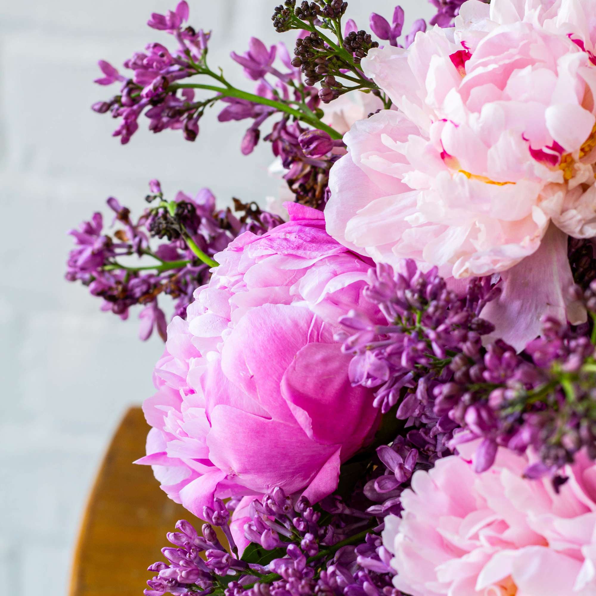 The beautiful arrangement features blush color peonies and purple lilacs gathered together