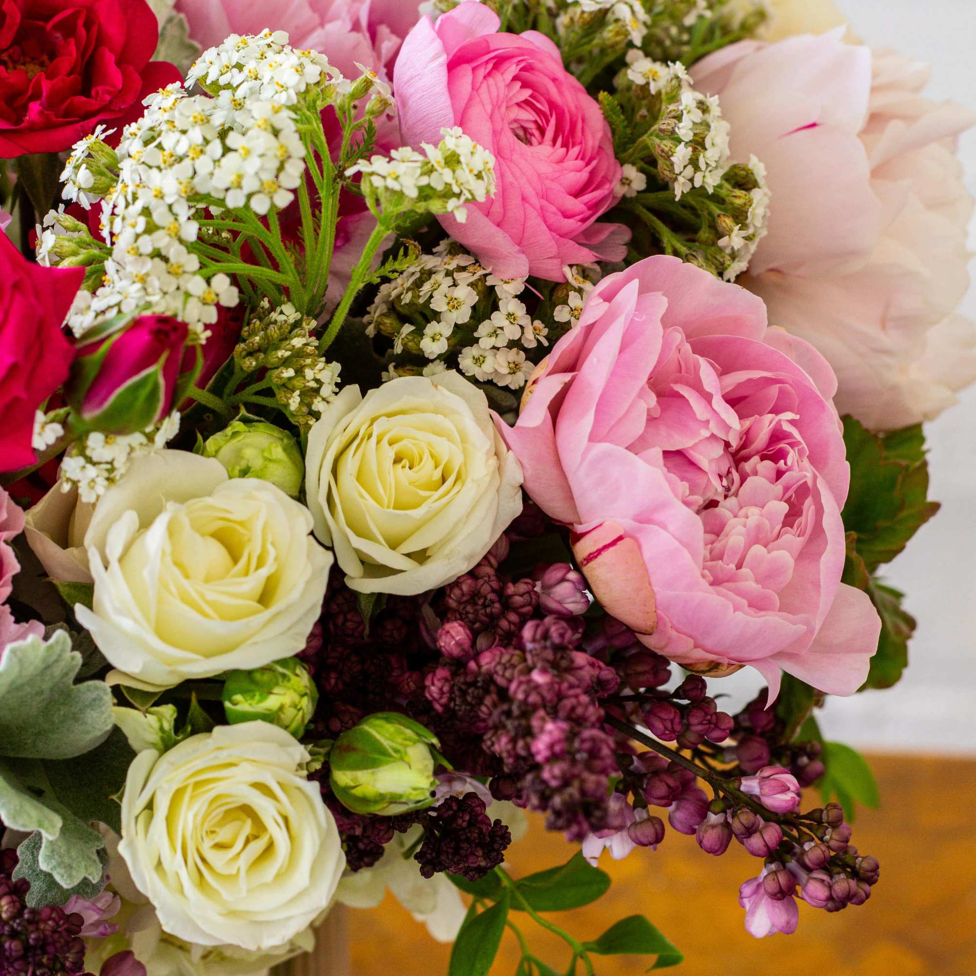 For this exquisite floral arrangement, envision a captivating blend of peonies, lilacs
