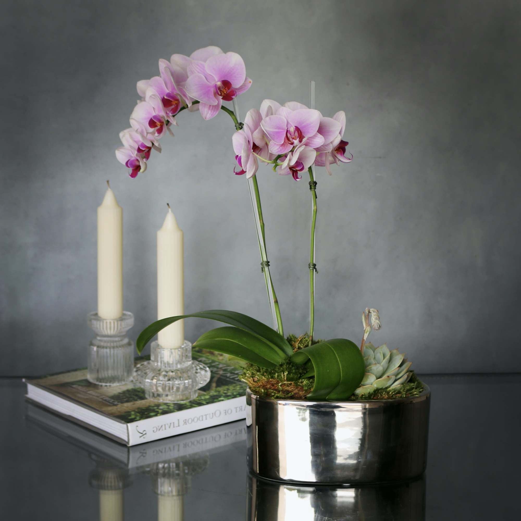 A simple pink mini Orchid arranged within a silver mini vase. Accented