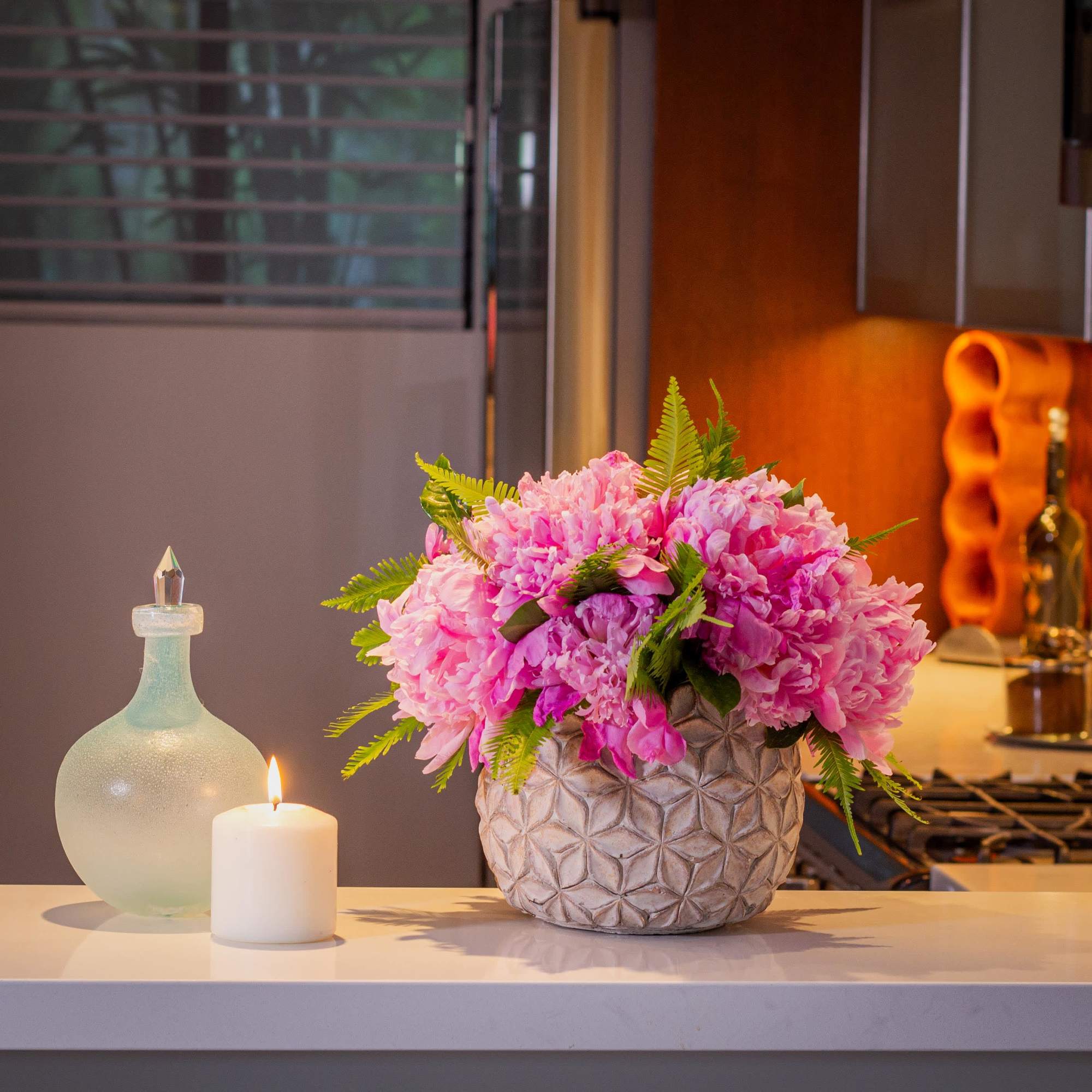 The vibrant clusters of various-colored peonies, accented by feather-like greenery and shiny