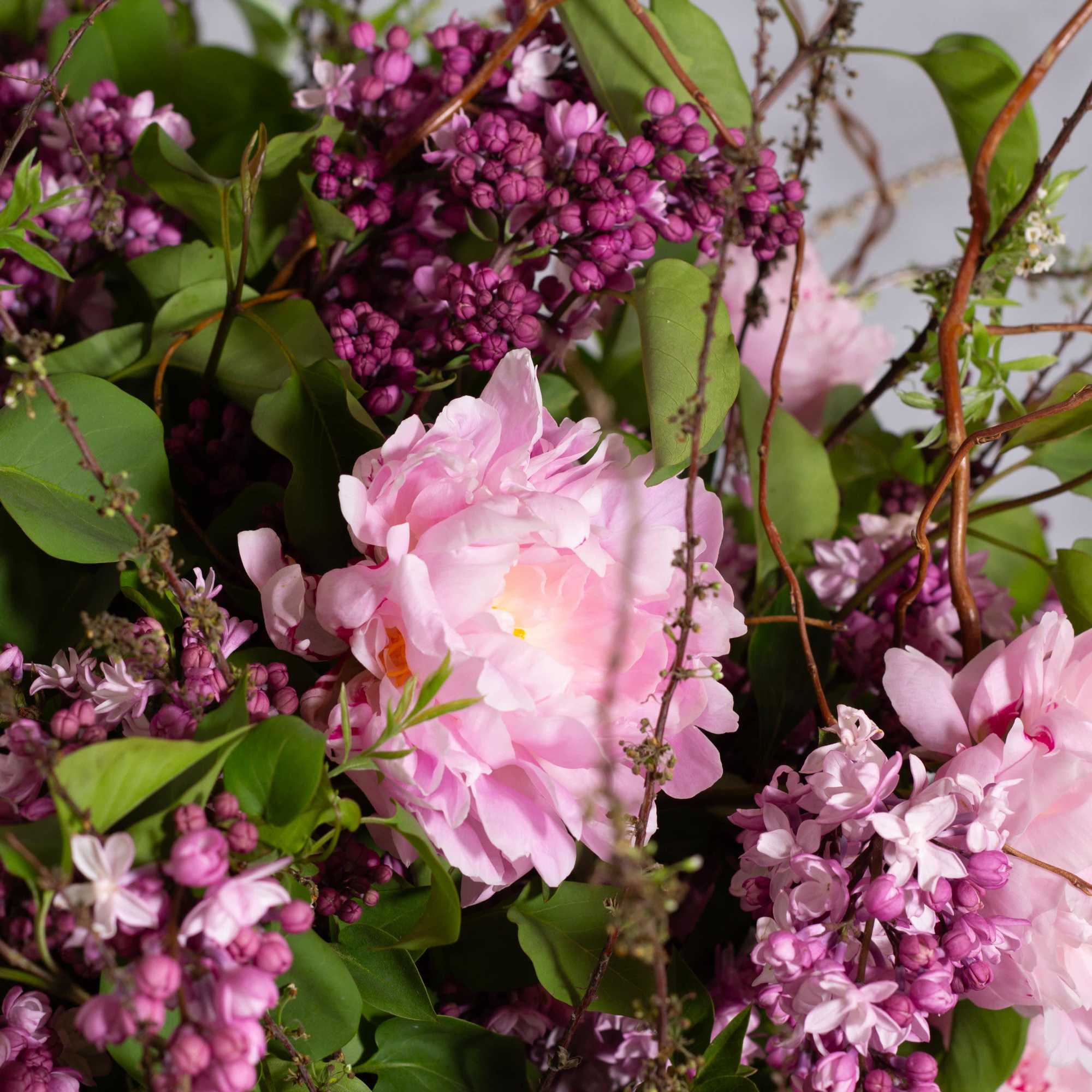The grand display features an organic arrangement of fragrant lilacs, peonies, and