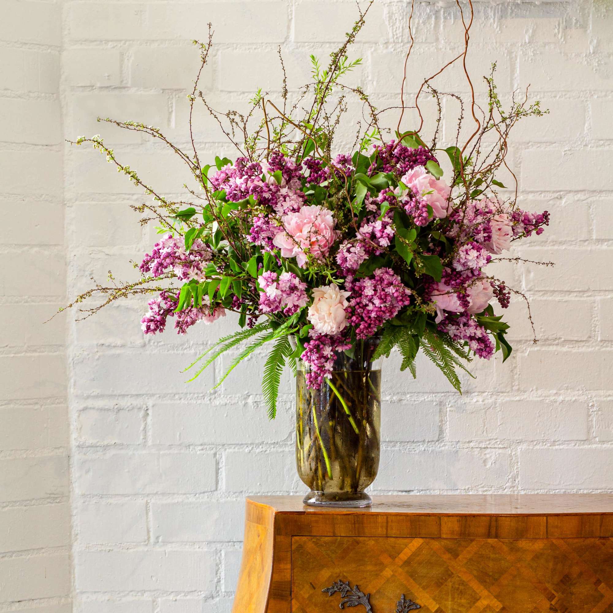 The grand display features an organic arrangement of fragrant lilacs, peonies, and