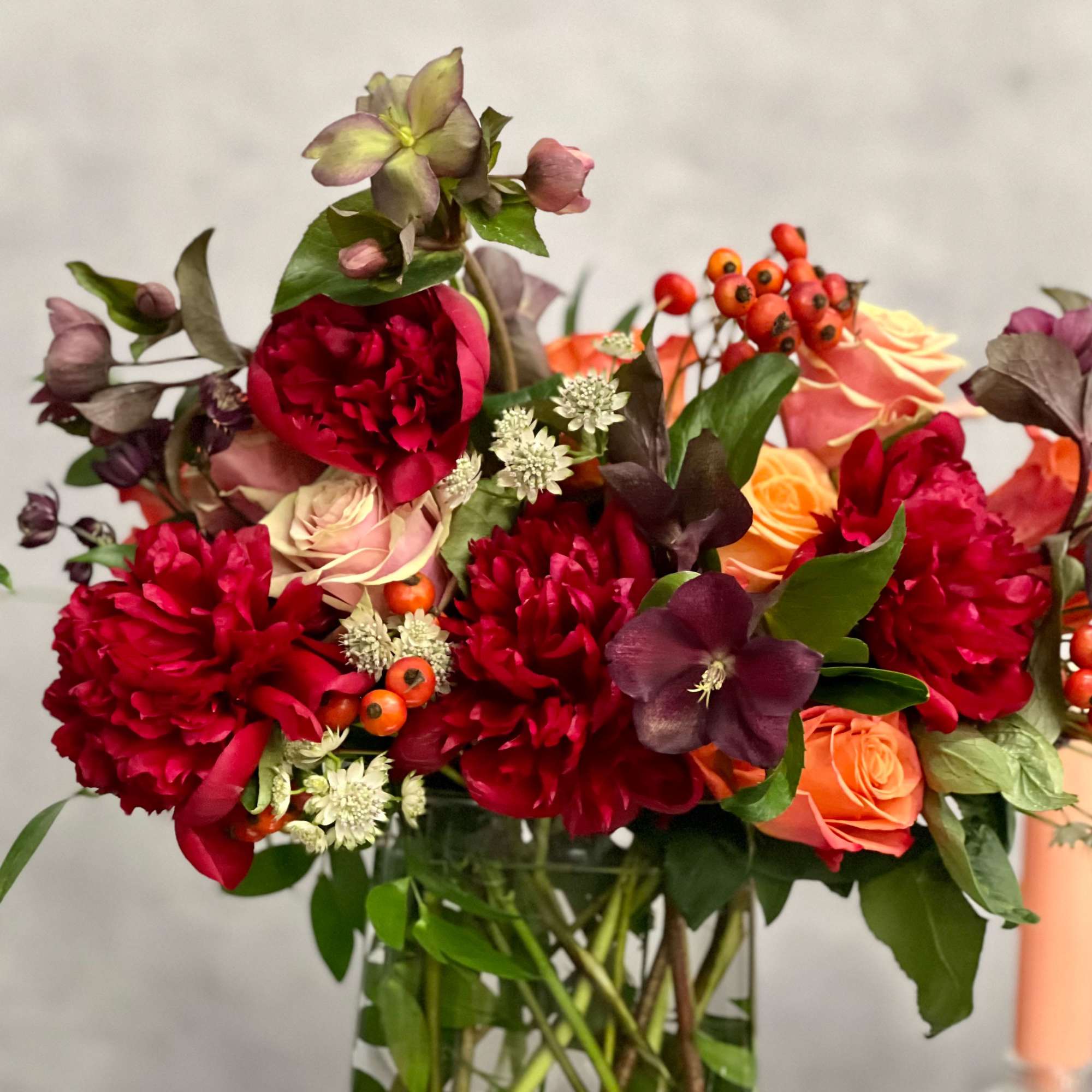 A majestic combination of orange roses, burgundy peonies and a variety of