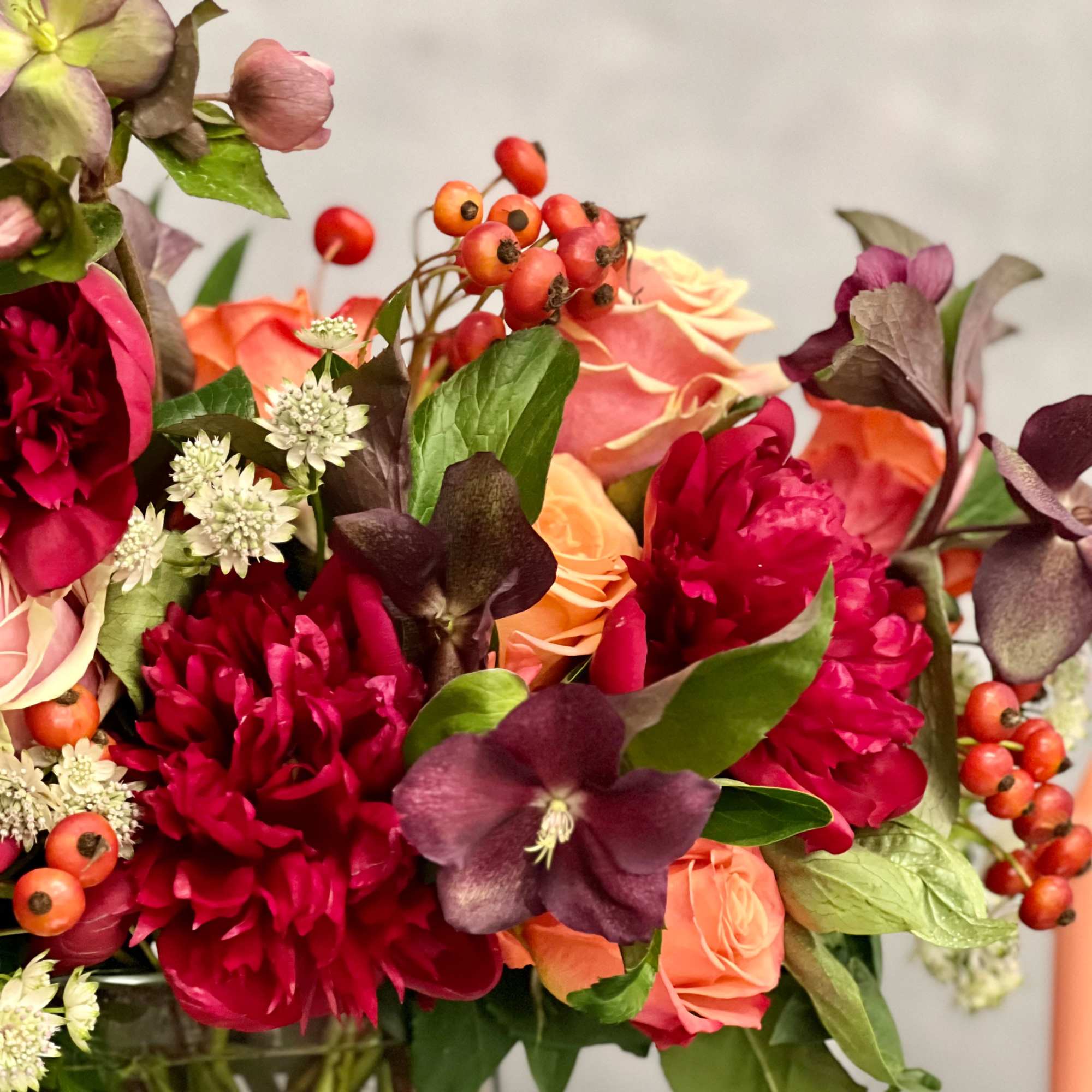A majestic combination of orange roses, burgundy peonies and a variety of