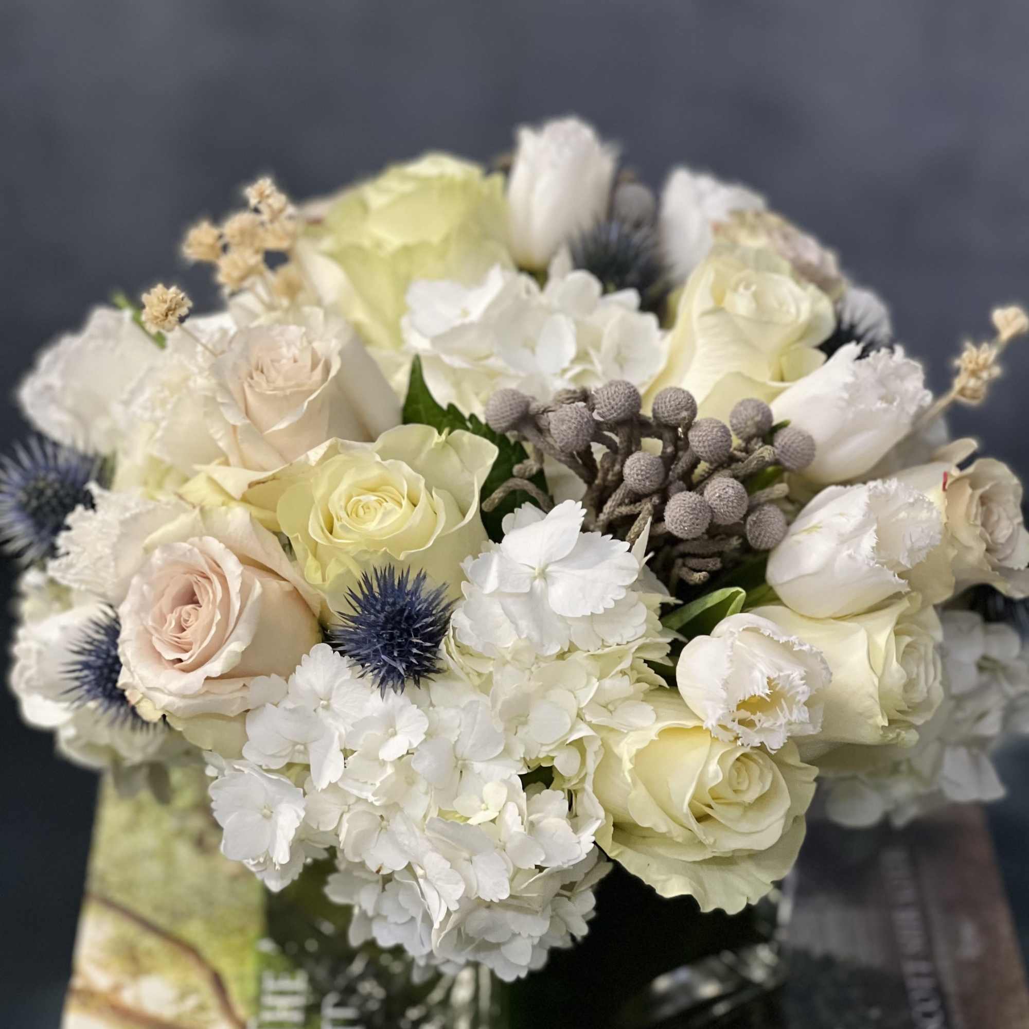 Our beautiful arrangement consists of White Roses, Hydrangeas, Thistles, Cream Roses placed