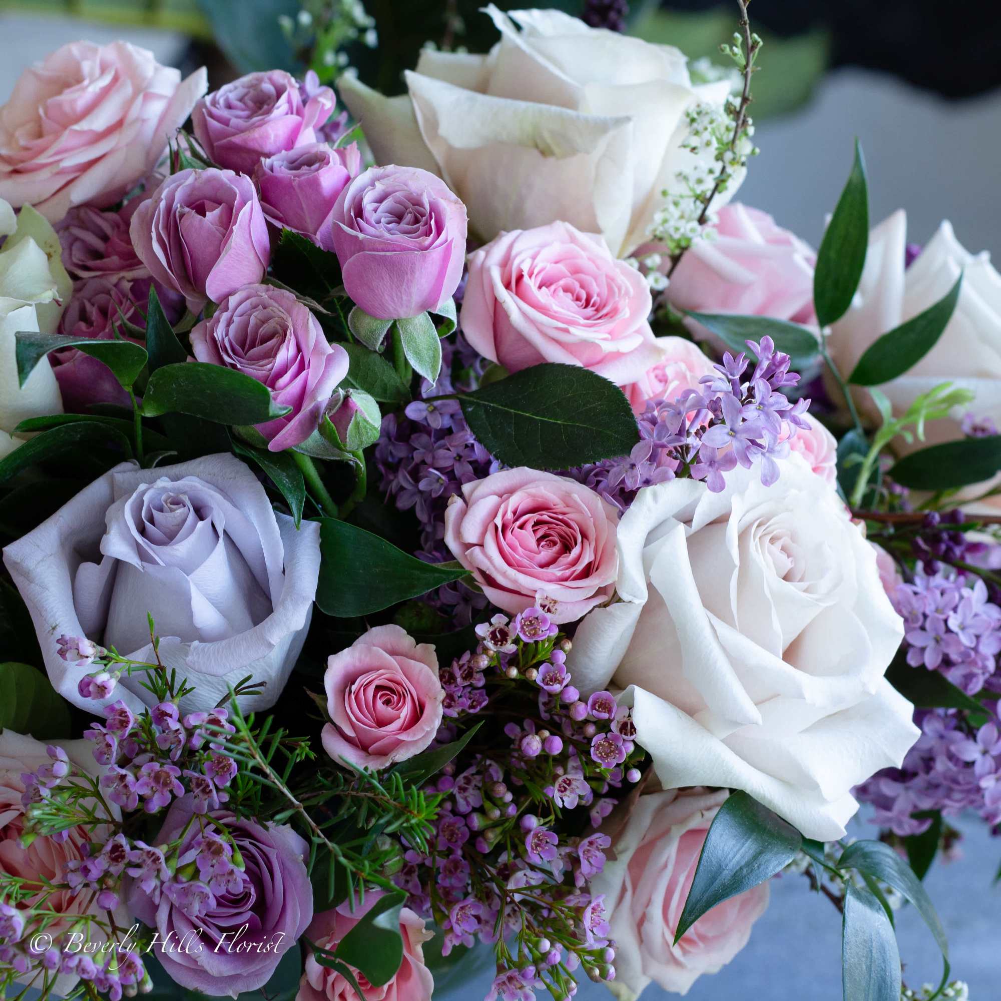 A beautiful floral arrangement featuring local lilacs and soft-colored roses set in