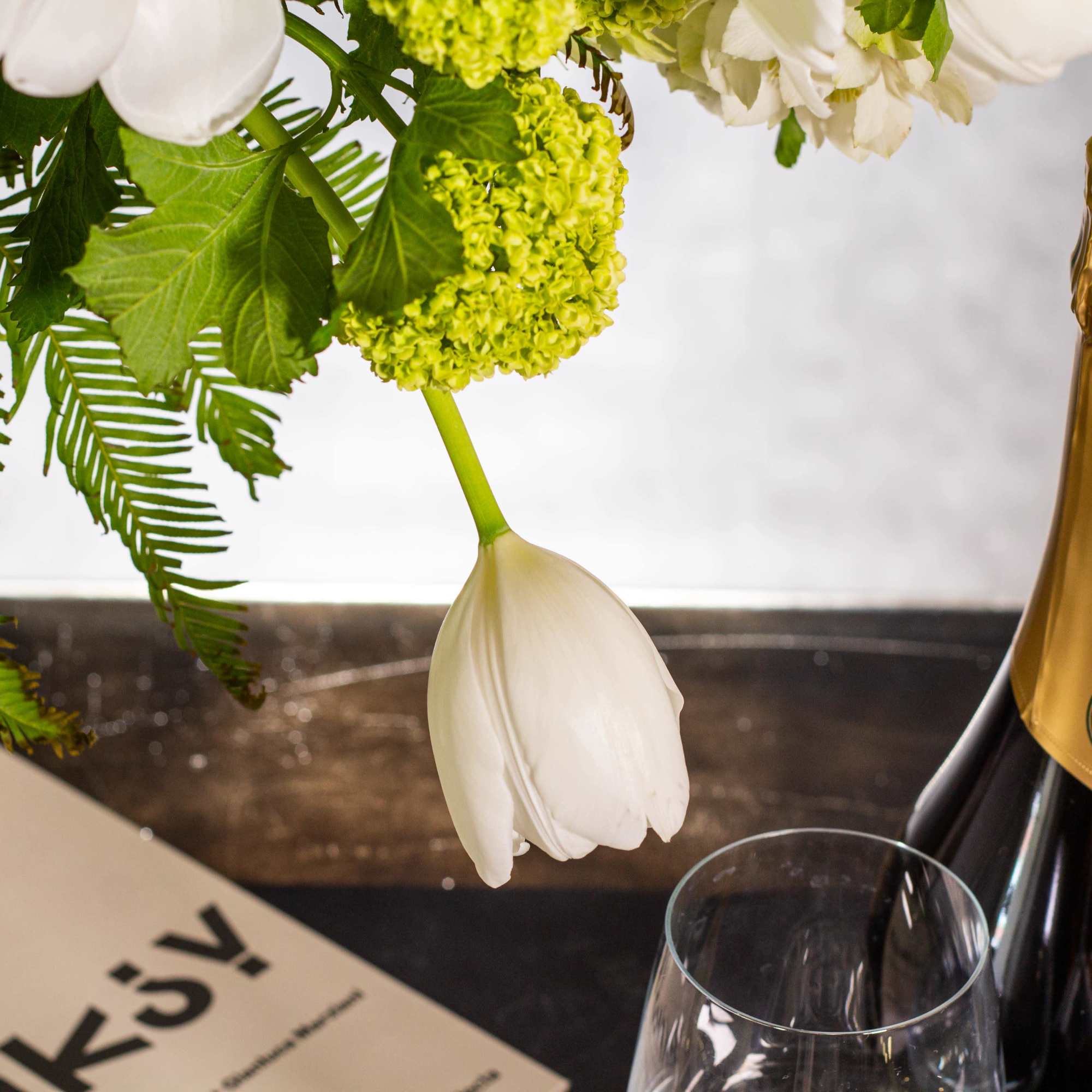 The beautiful arrangement features long white tulips, snapdragons, boulevard beautiful umbrella ferns