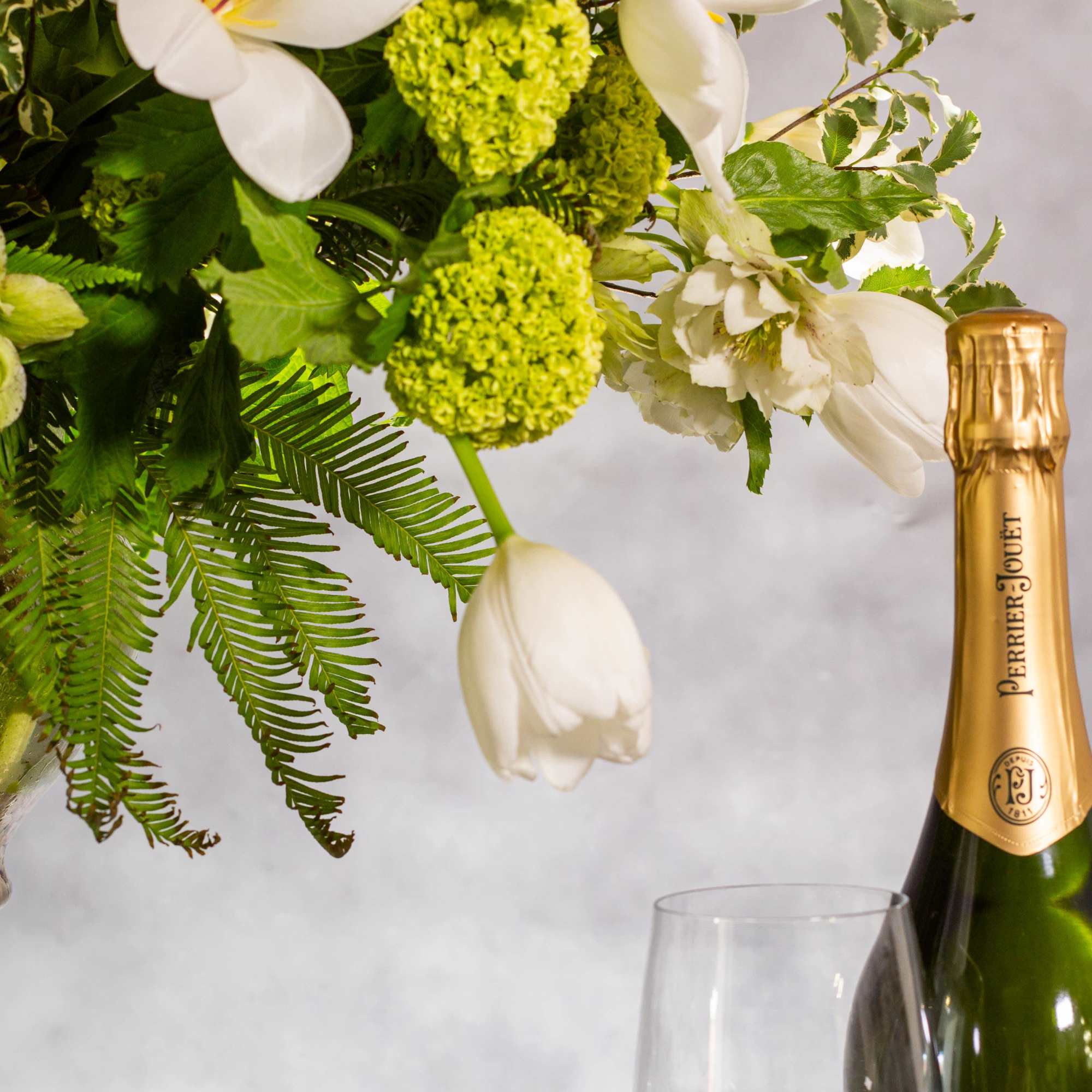 The beautiful arrangement features long white tulips, snapdragons, boulevard beautiful umbrella ferns