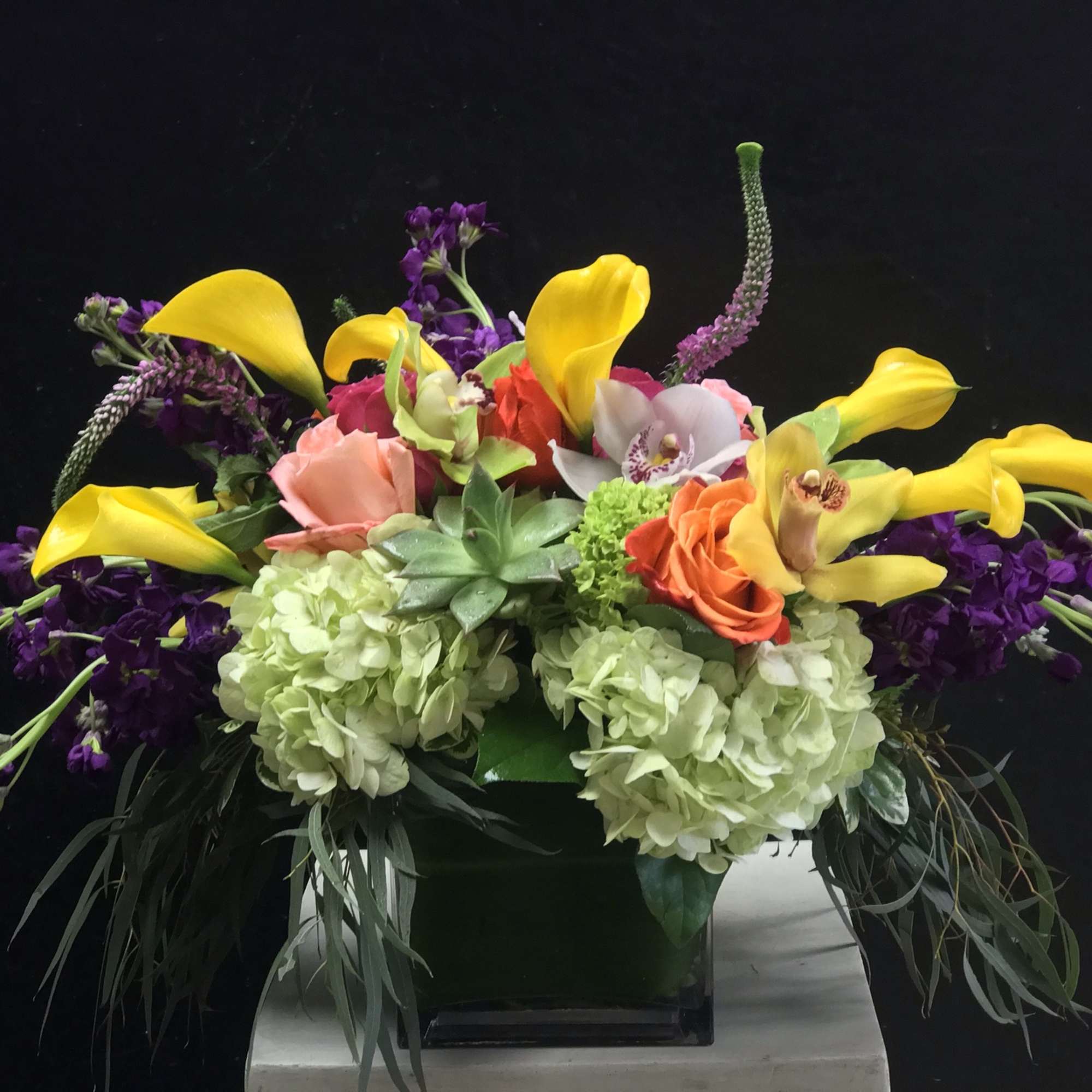 A verdant spilling-all-over table piece featuring callas, textured greenery, succulents, and orchids.