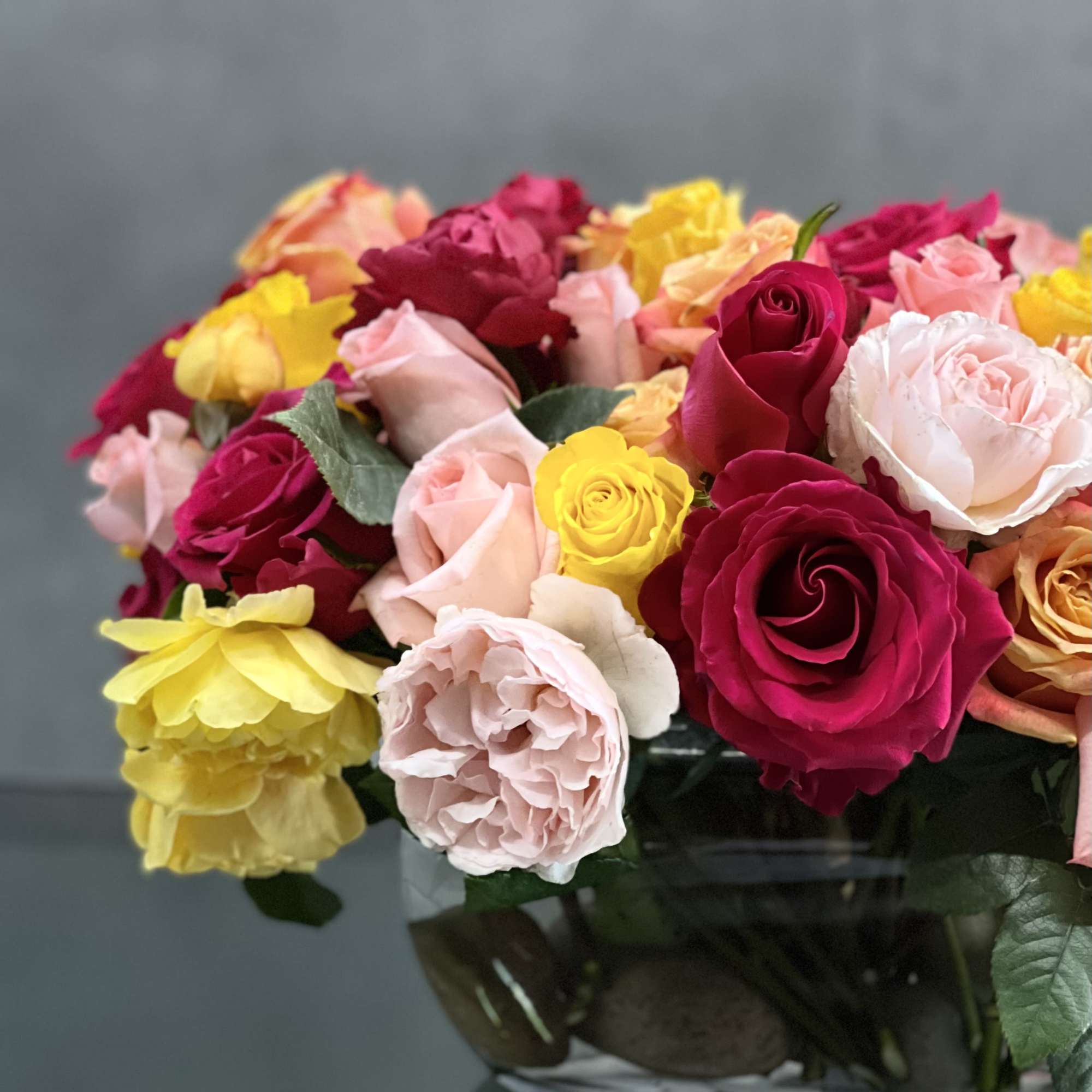 This arrangement of colorful roses  in an oval glass vase is