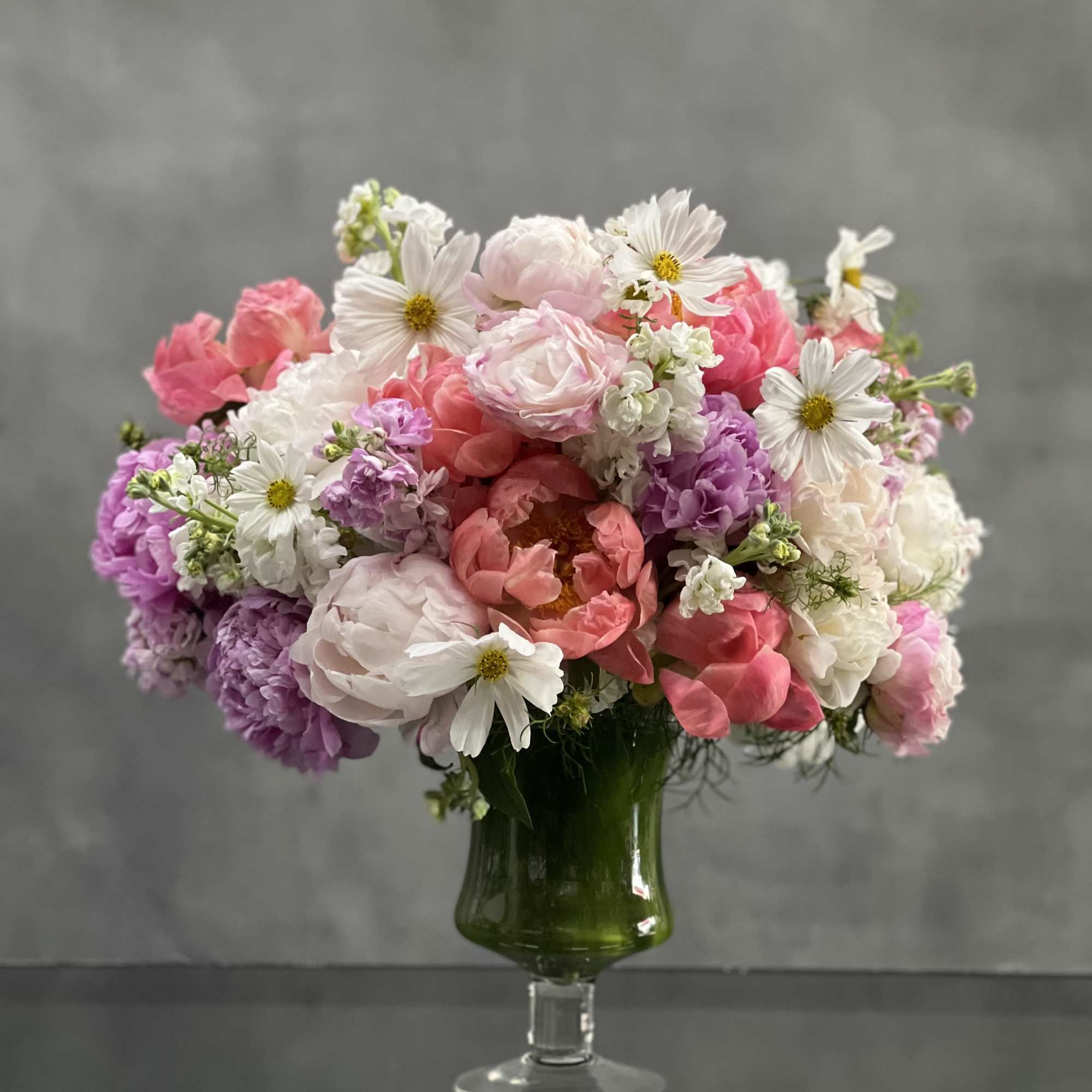This pedestal glass vase bursts with bloom upon bloom of gorgeous pinks