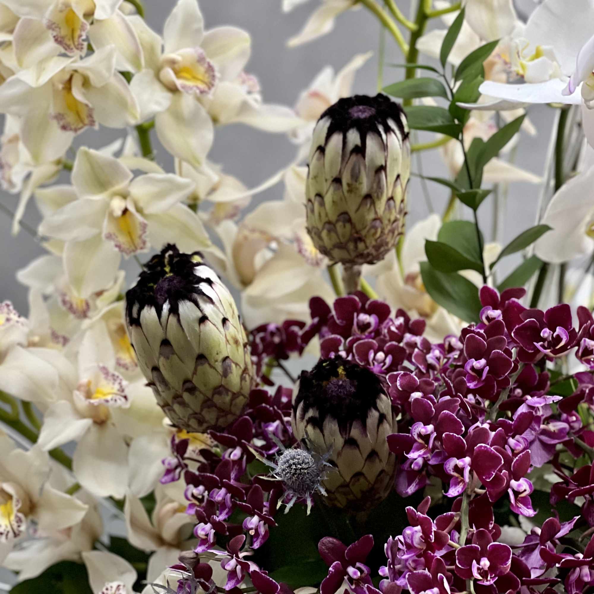 Overflowing of assorted Orchids artfully arranged in tall pedestal vase. This is