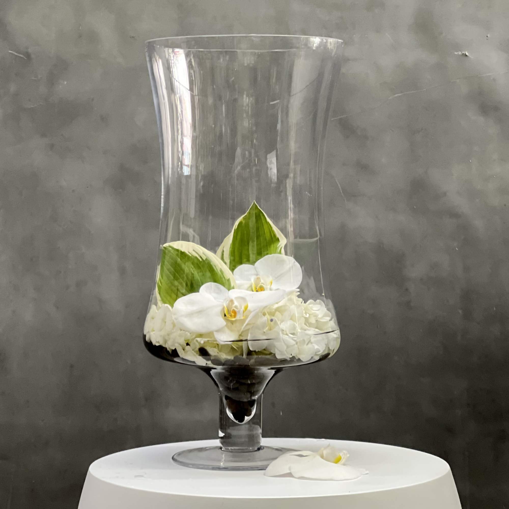 Overflowing of assorted Orchids artfully arranged in tall pedestal vase. This is