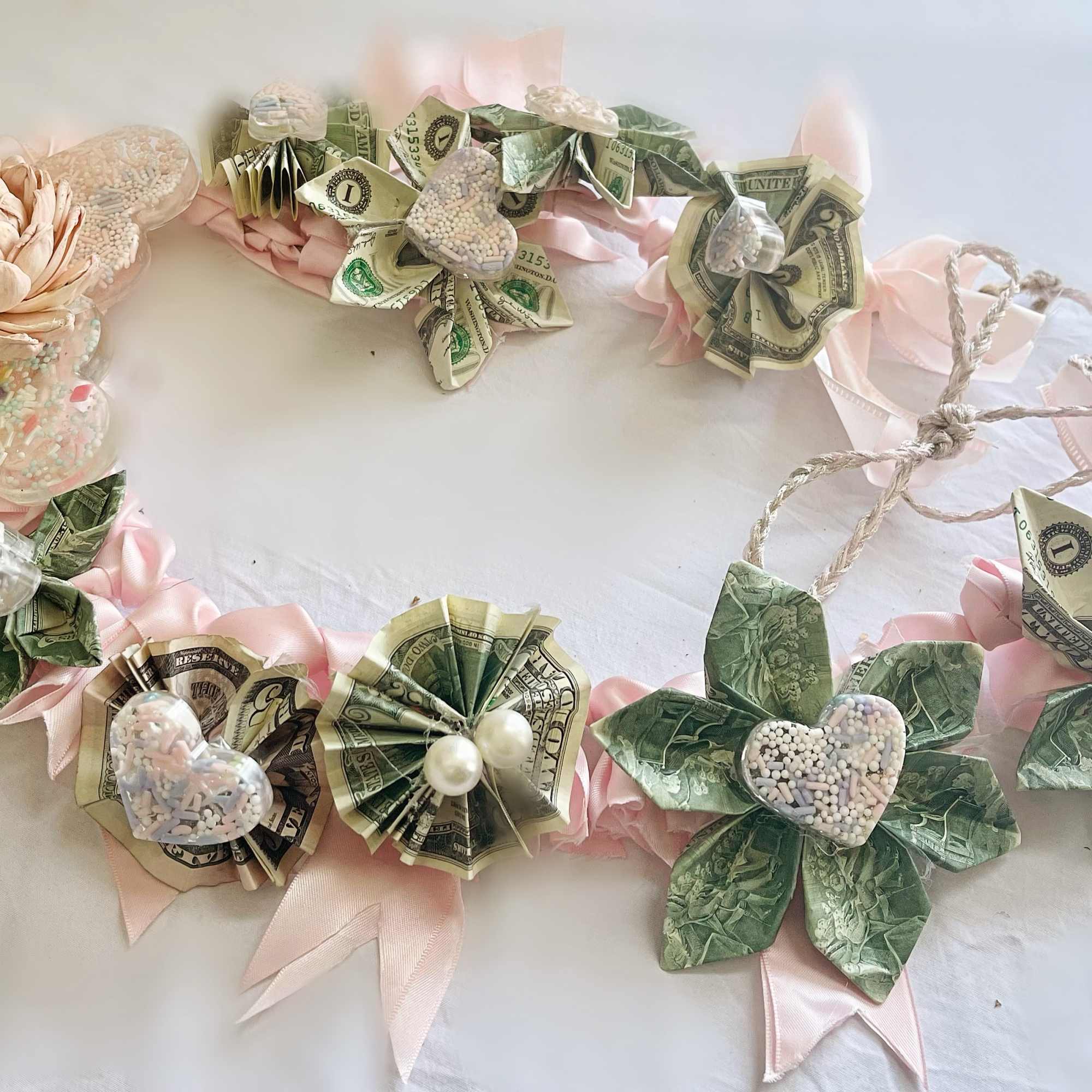 A graduation money lei focused on origami style flowers and blush ribbon