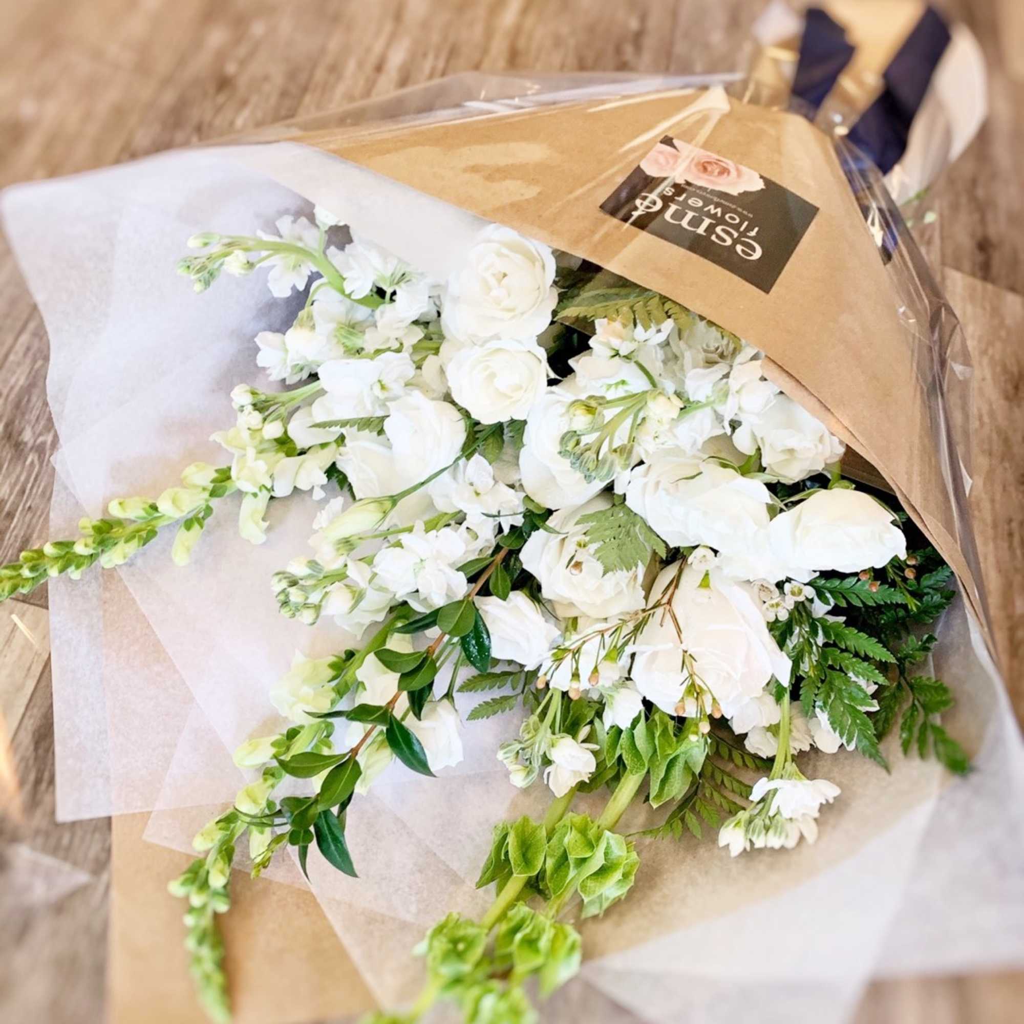An elegant wrapped bouquet of all white premium flowers and greenery for An elegant wrapped bouquet of all white premium flowers and greenery for