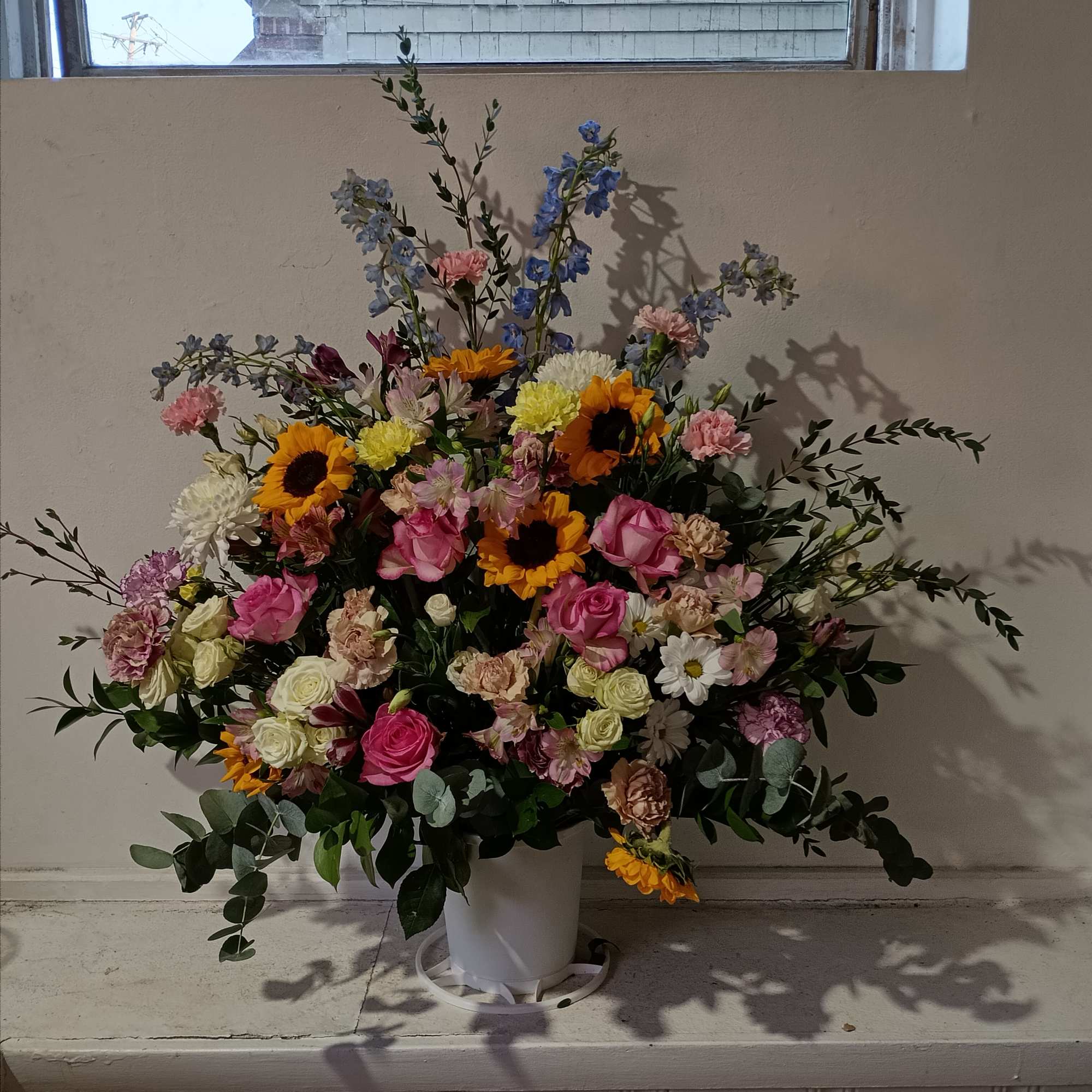 Beautiful sympathy basket with sunflowers, pale pink carnations, pink roses and delphinium