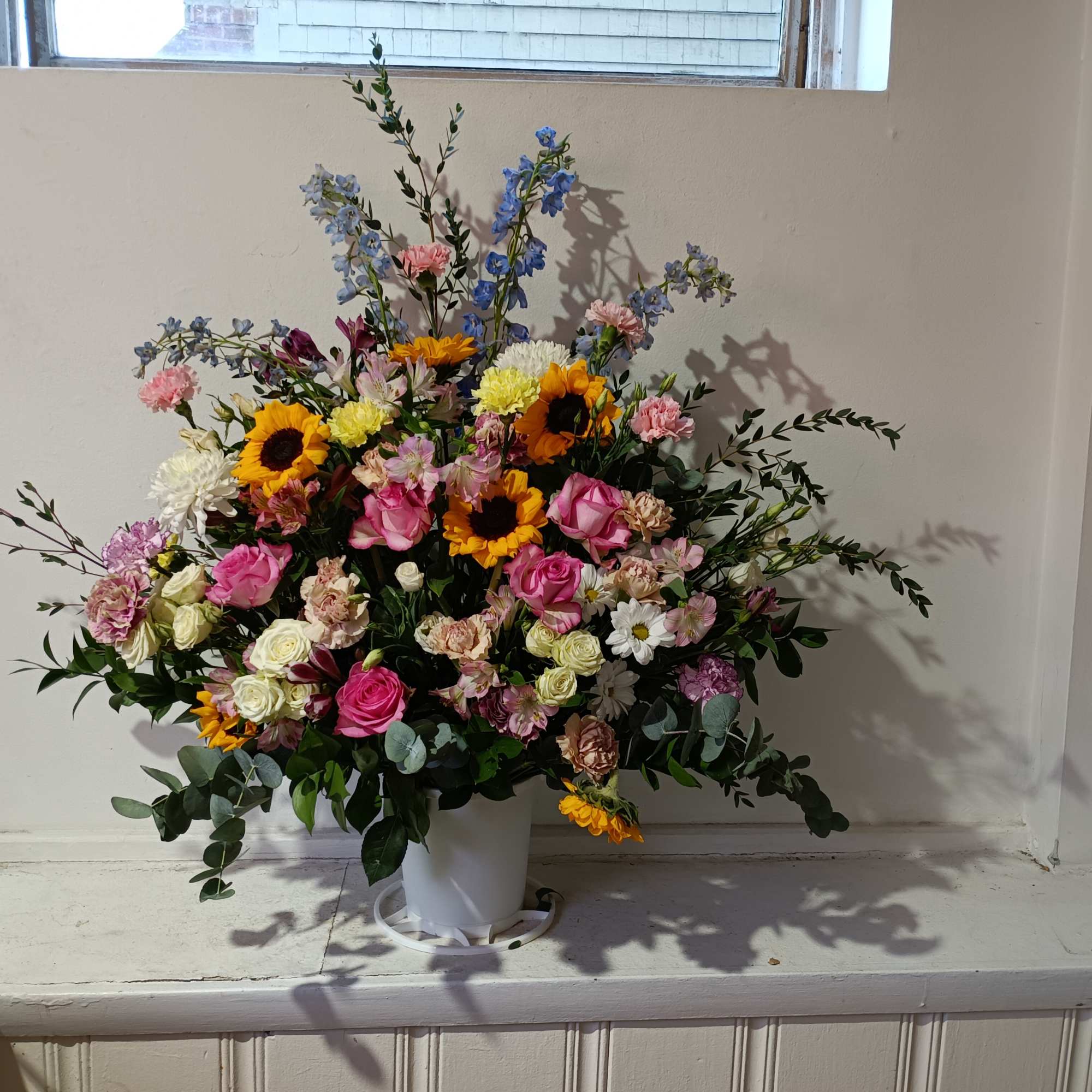 Beautiful sympathy basket with sunflowers, pale pink carnations, pink roses and delphinium