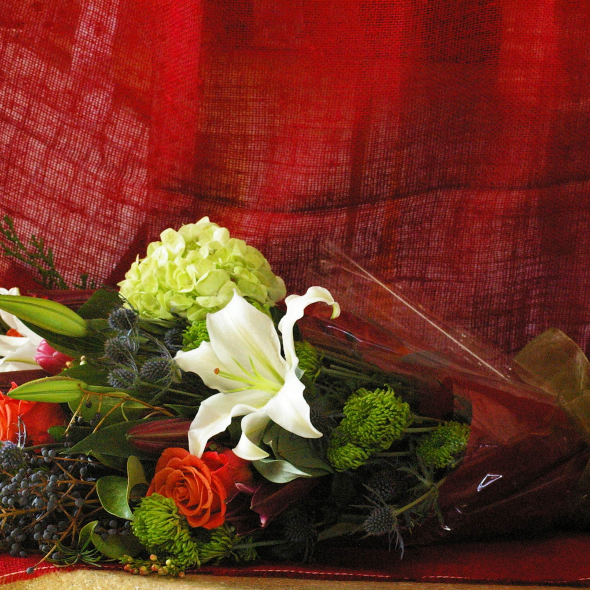 Winter arm bouquet with casablanca lilies, protea, blue thistle, coral roses, wax
