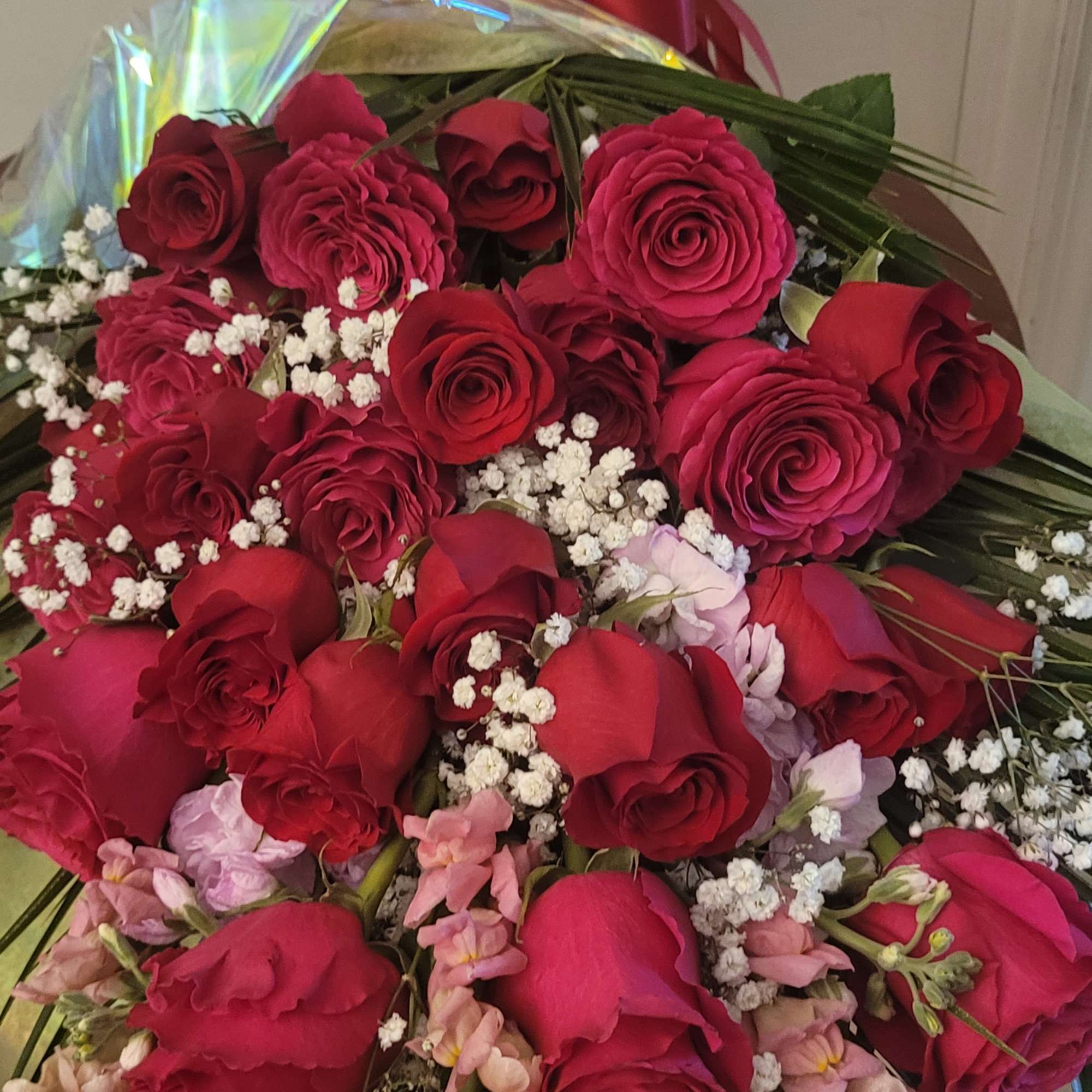 A traditional, all-rose presentation bouquet, with greens and filler flowers, wrapped with