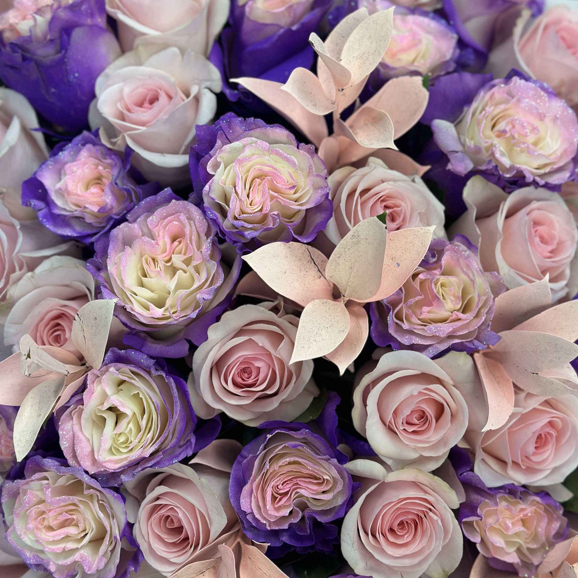 Composition: The bouquet features a variety of pink and purple roses as