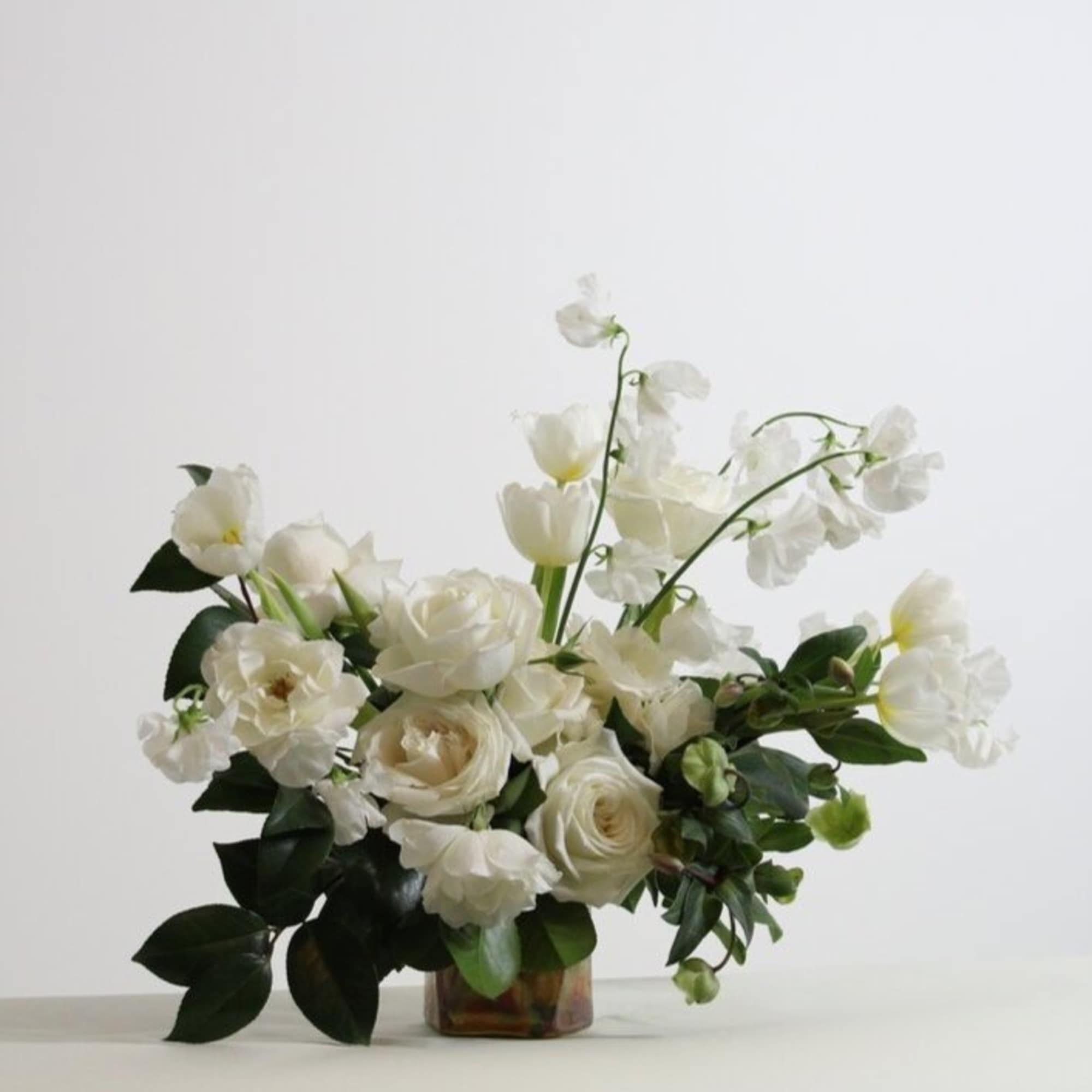 - Garden-inspired floral arrangement bursting with pristine white roses and lush green