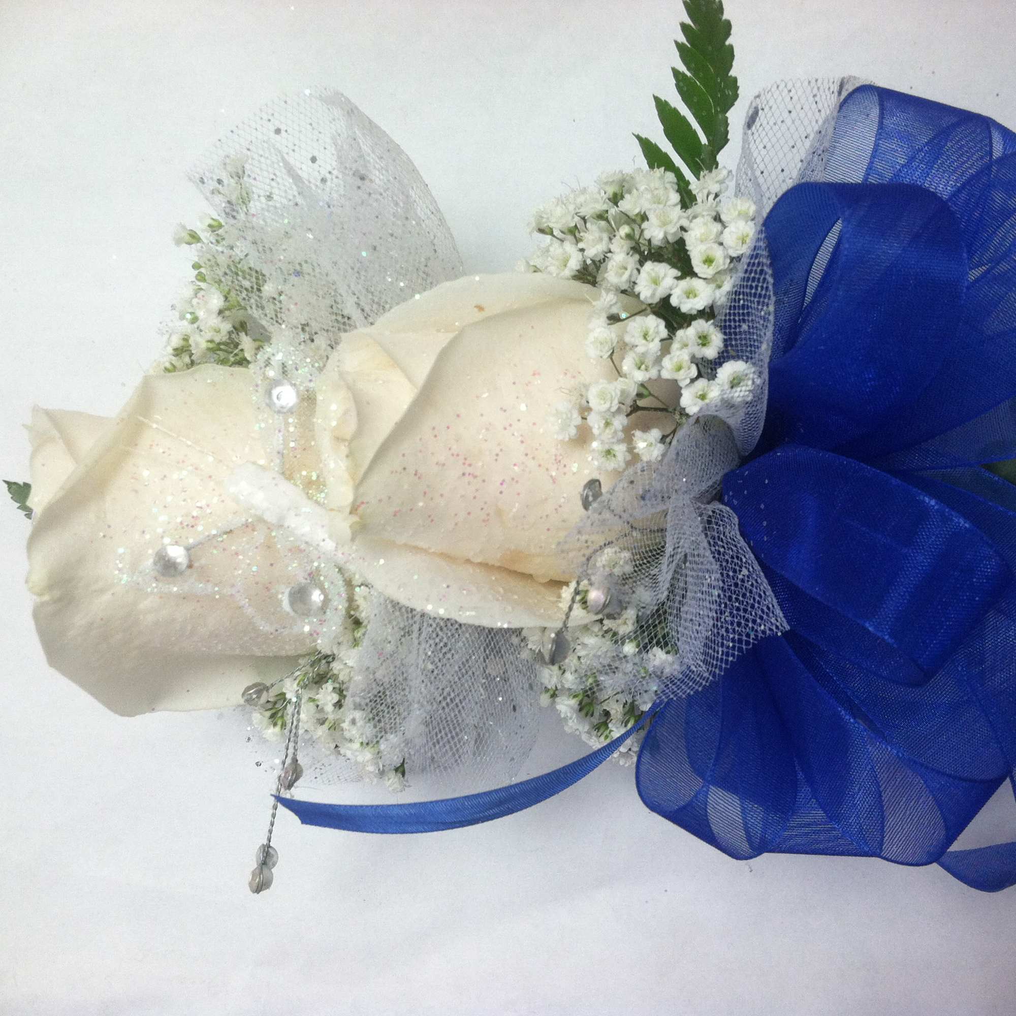 A classic white corsage with silver sheer ribbon, this wrist arrangement looks