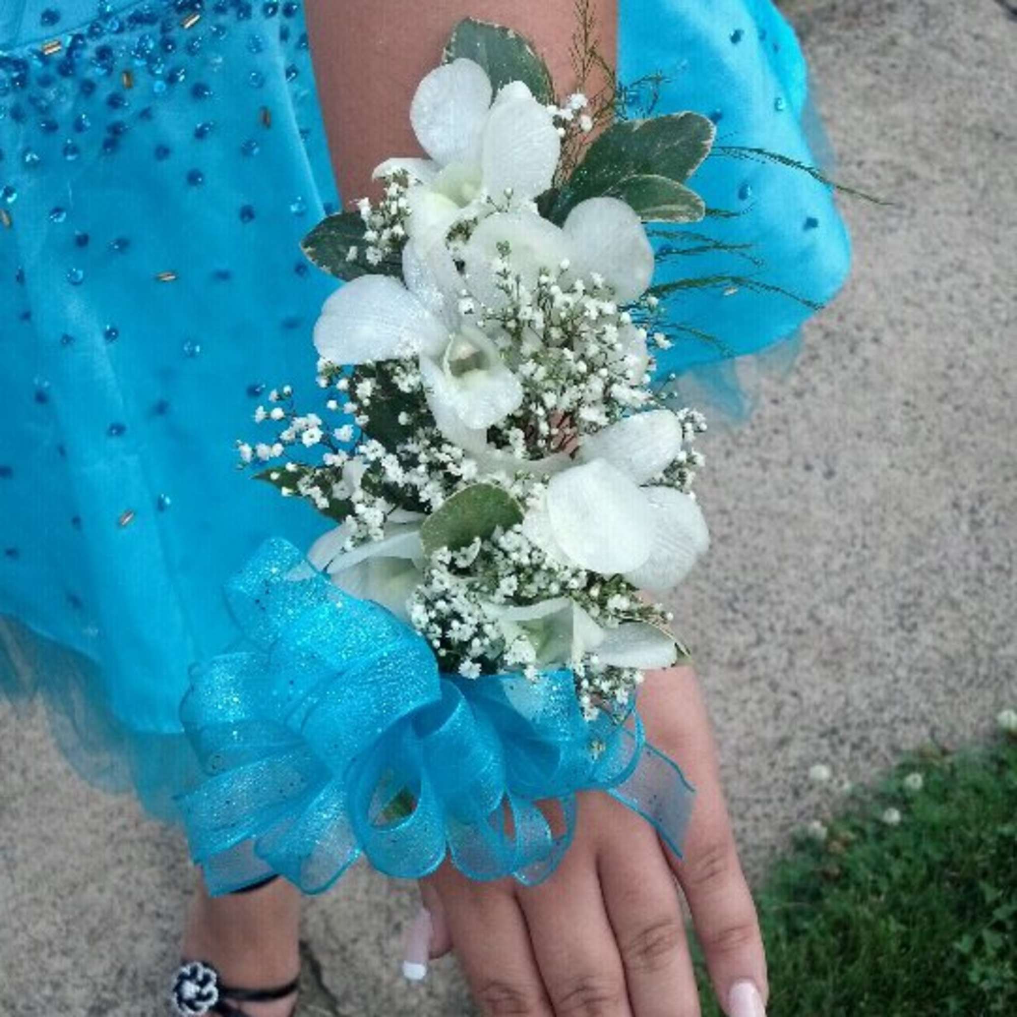 A classic white corsage with silver sheer ribbon, this wrist arrangement looks