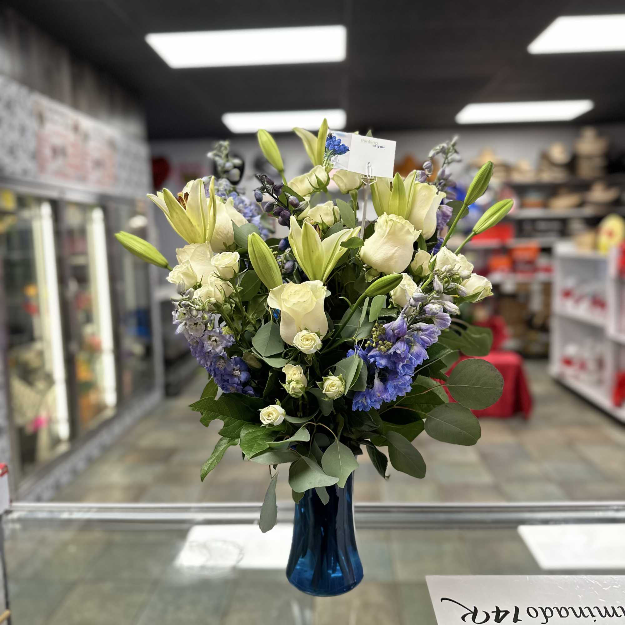 This exquisite sympathy tribute features fresh white roses, lilies, delphine, spray roses