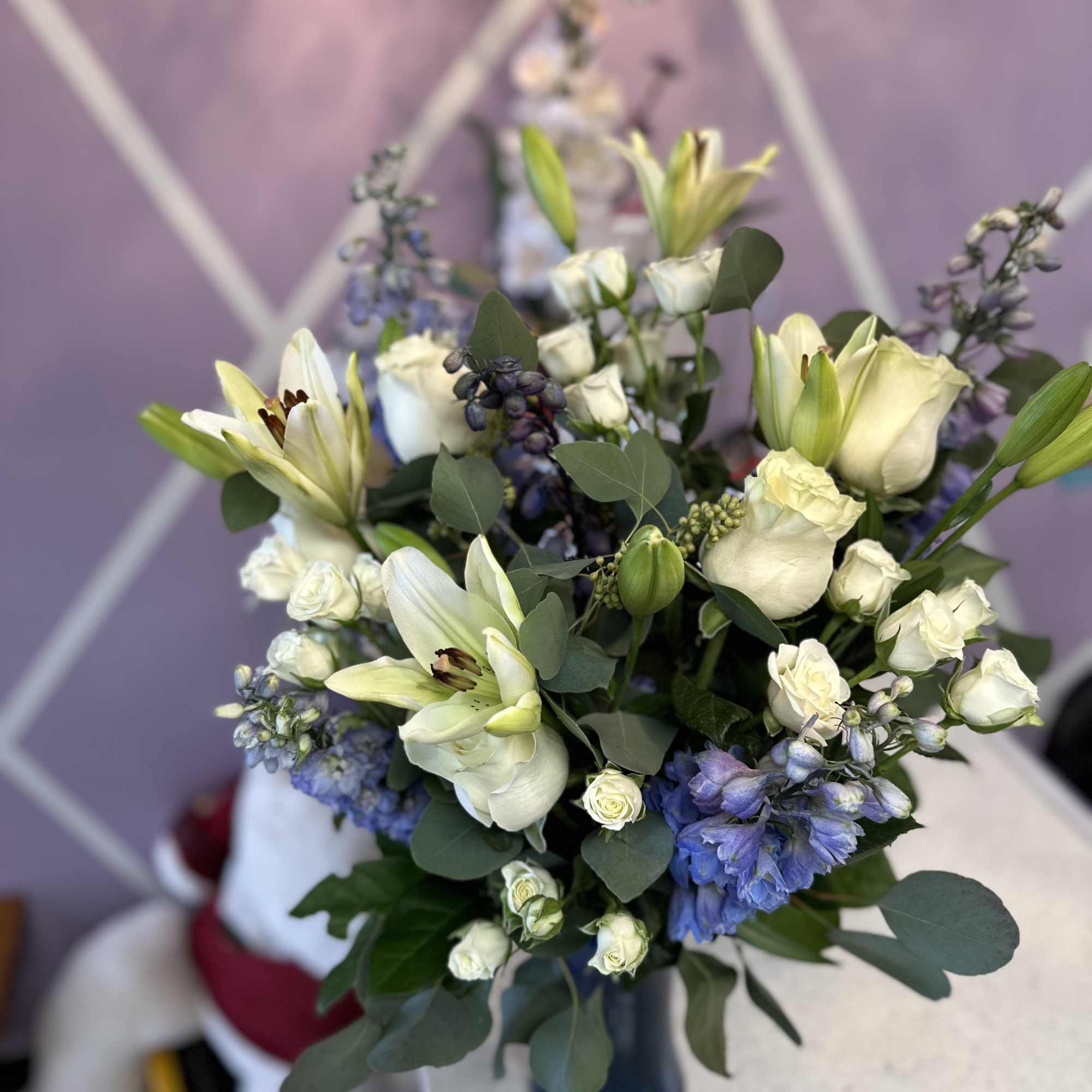 This exquisite sympathy tribute features fresh white roses, lilies, delphine, spray roses