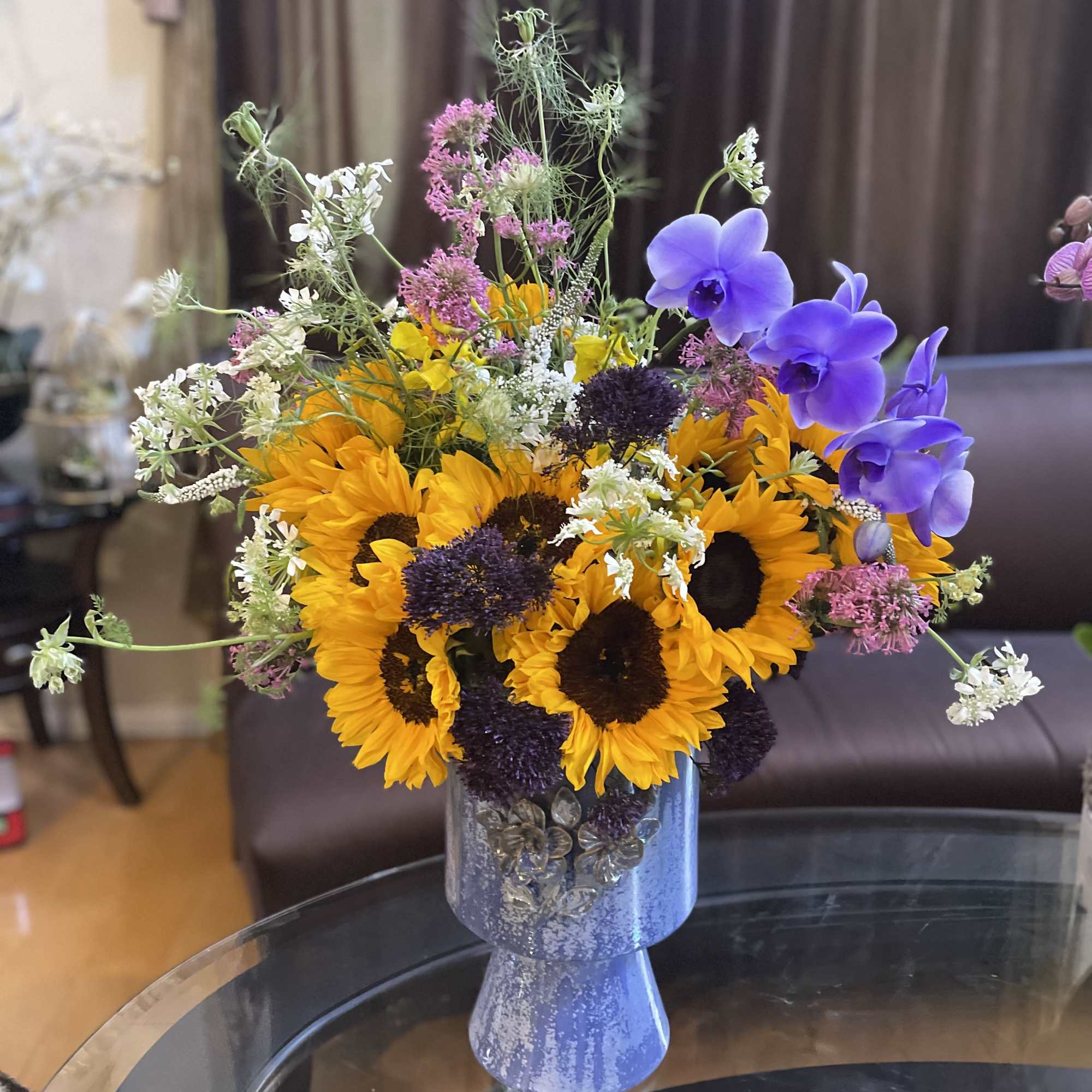 This striking floral arrangement features the vibrant beauty of sunflowers contrasted with