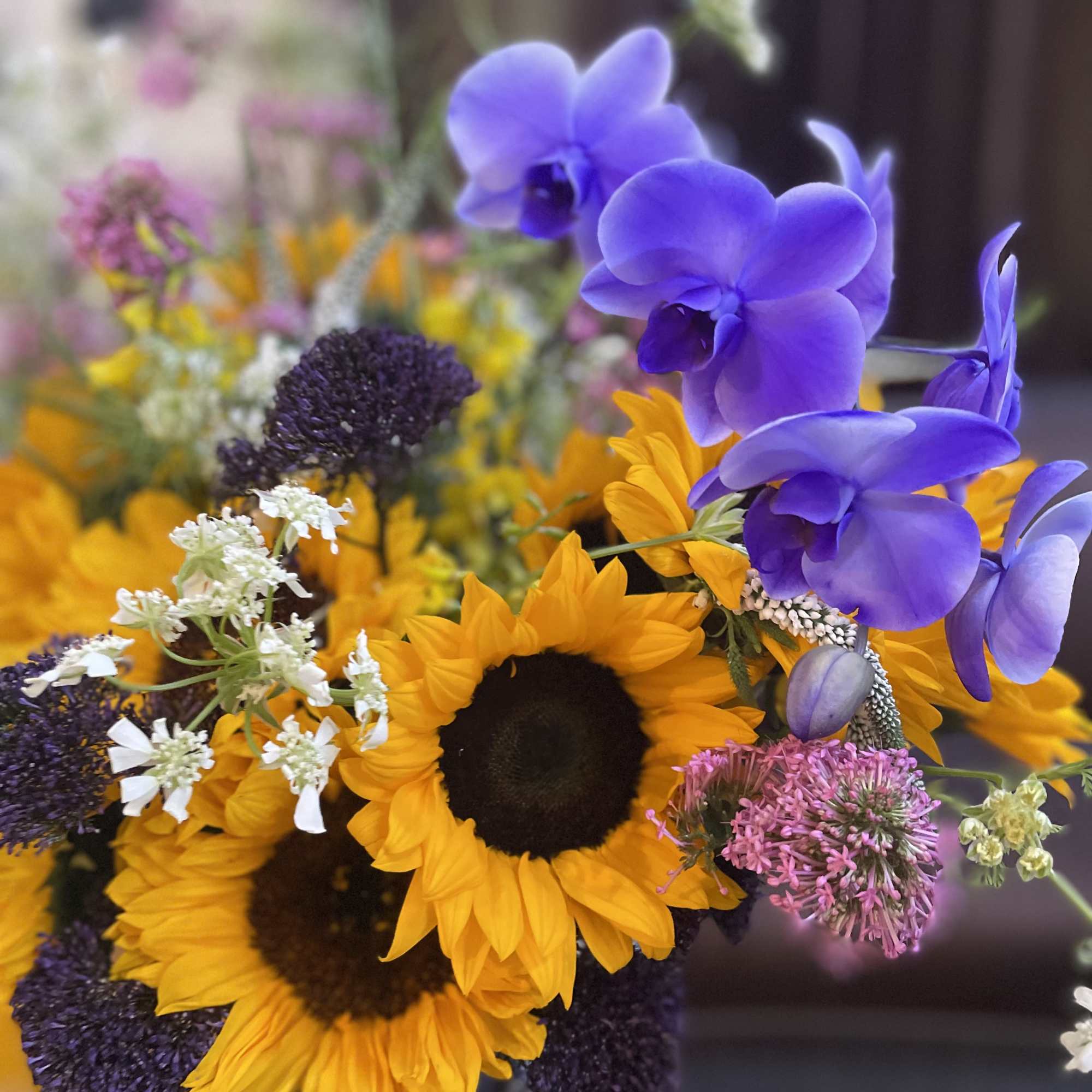 This striking floral arrangement features the vibrant beauty of sunflowers contrasted with