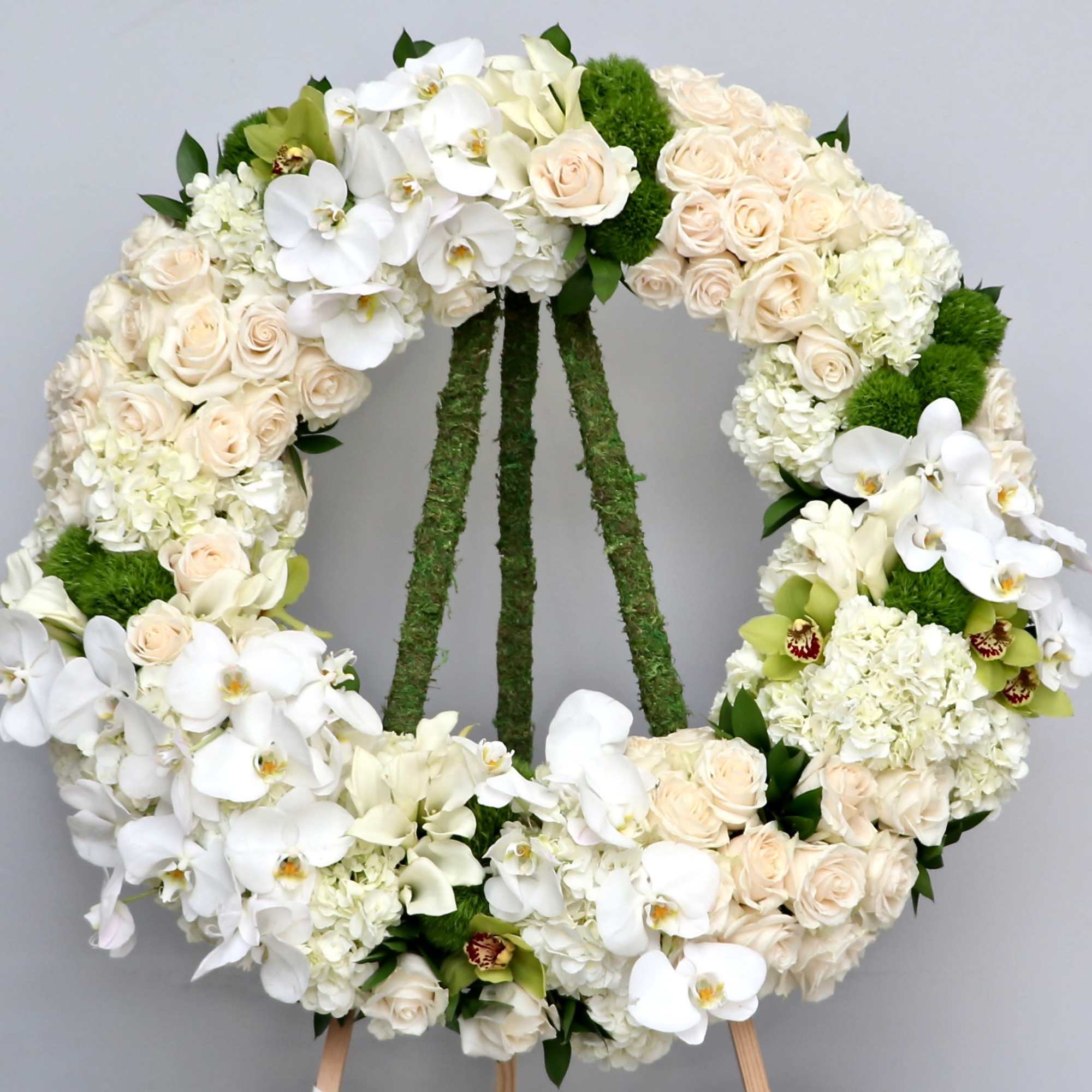 This wreath contains a mix of white orchids, hydrangeas and seasonal greens.