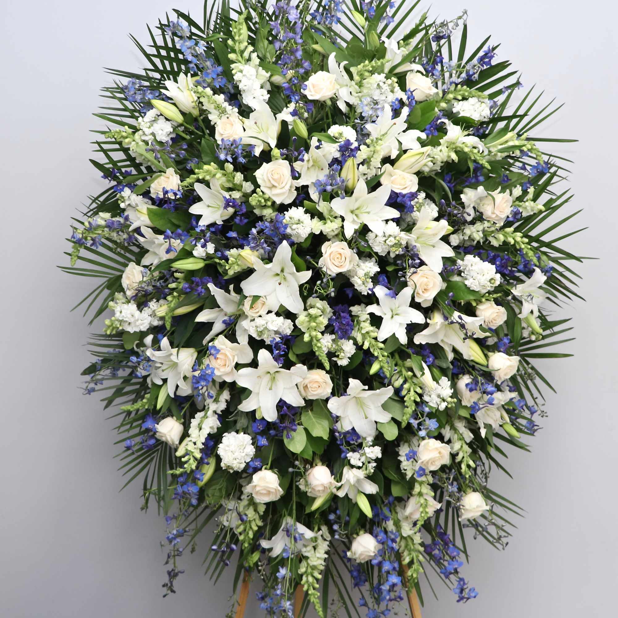 This spray is made with white roses and lilies with blue delphiniums
