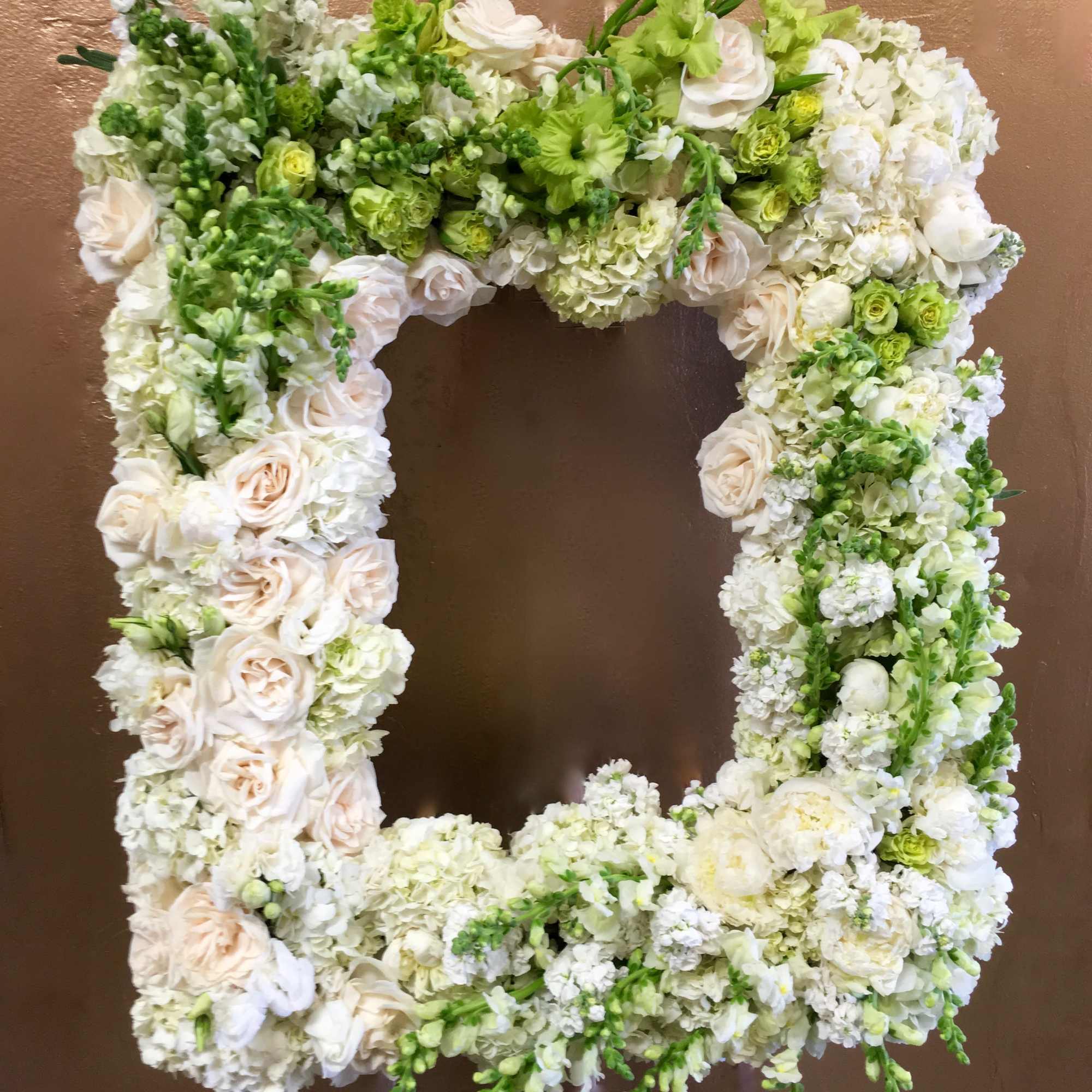 This frame includes white and green roses as well as matching snapdragons.