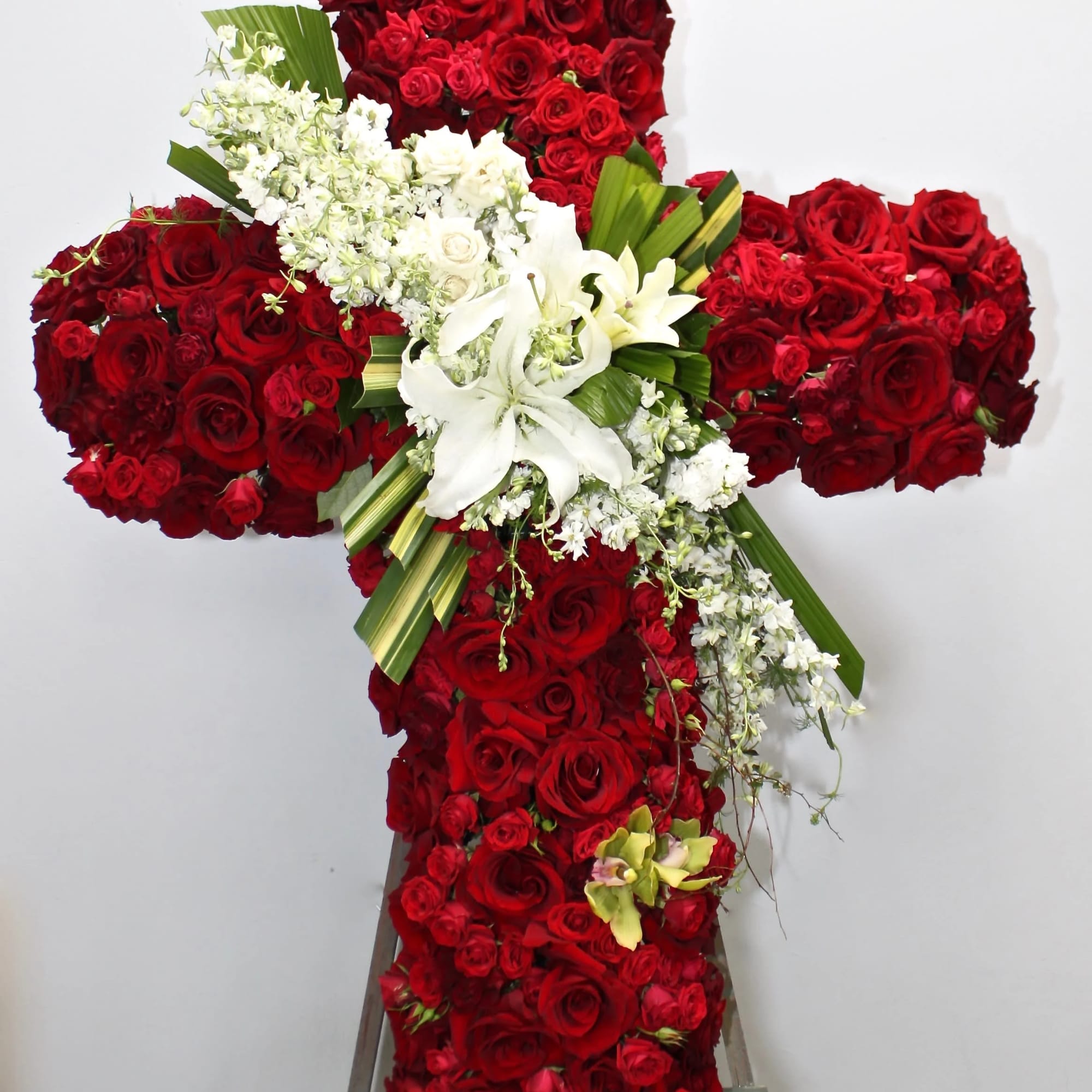This cross contains red roses of various sizes as well as a