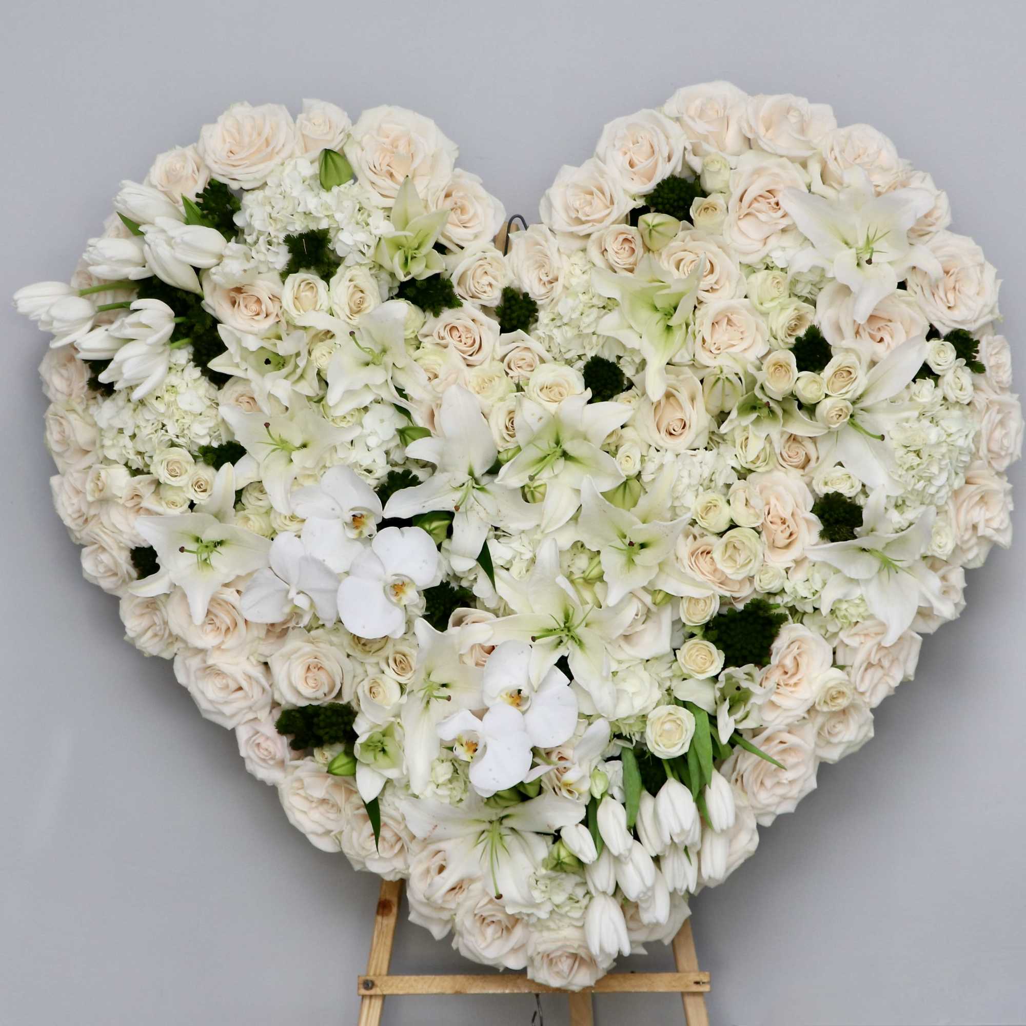 This white and green heart contains a beautiful mix of orchids, stargazer