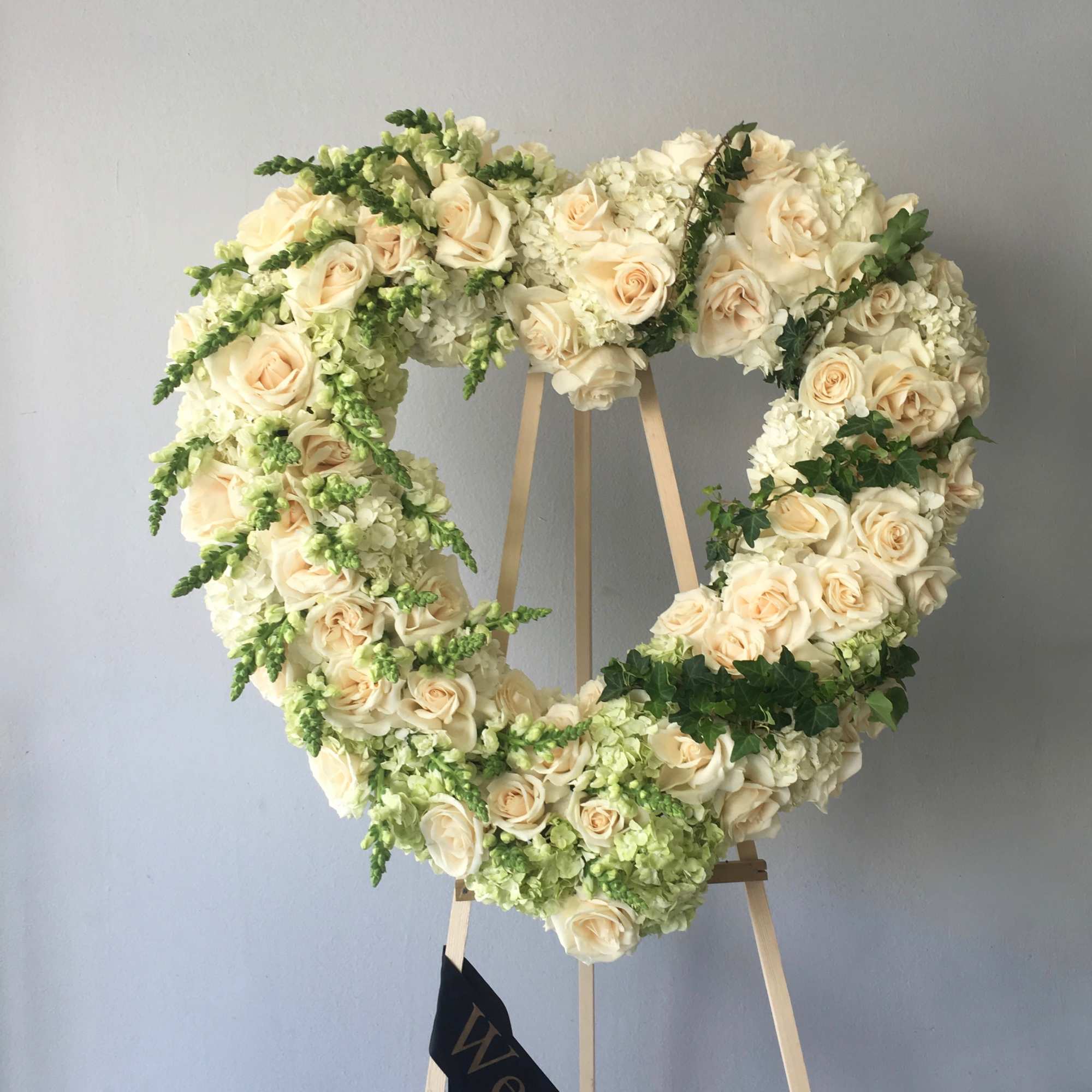 This sympathy heart contains roses, hydrangeas, and seasonal greens, all arranged in