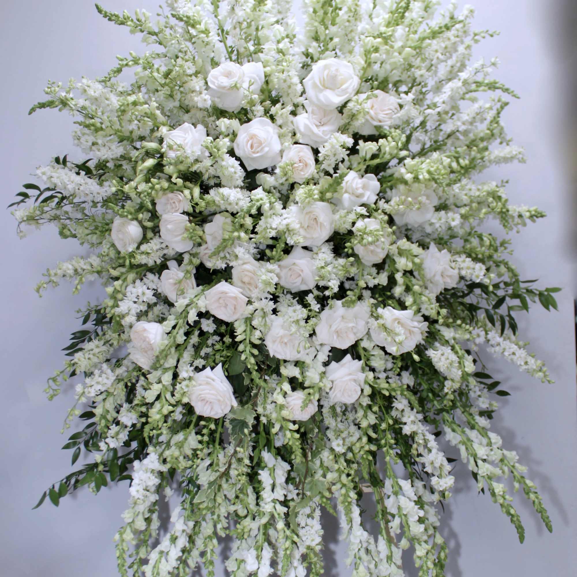 This classic sympathy spray includes roses, snapdragons and seasonal greens. 

We include