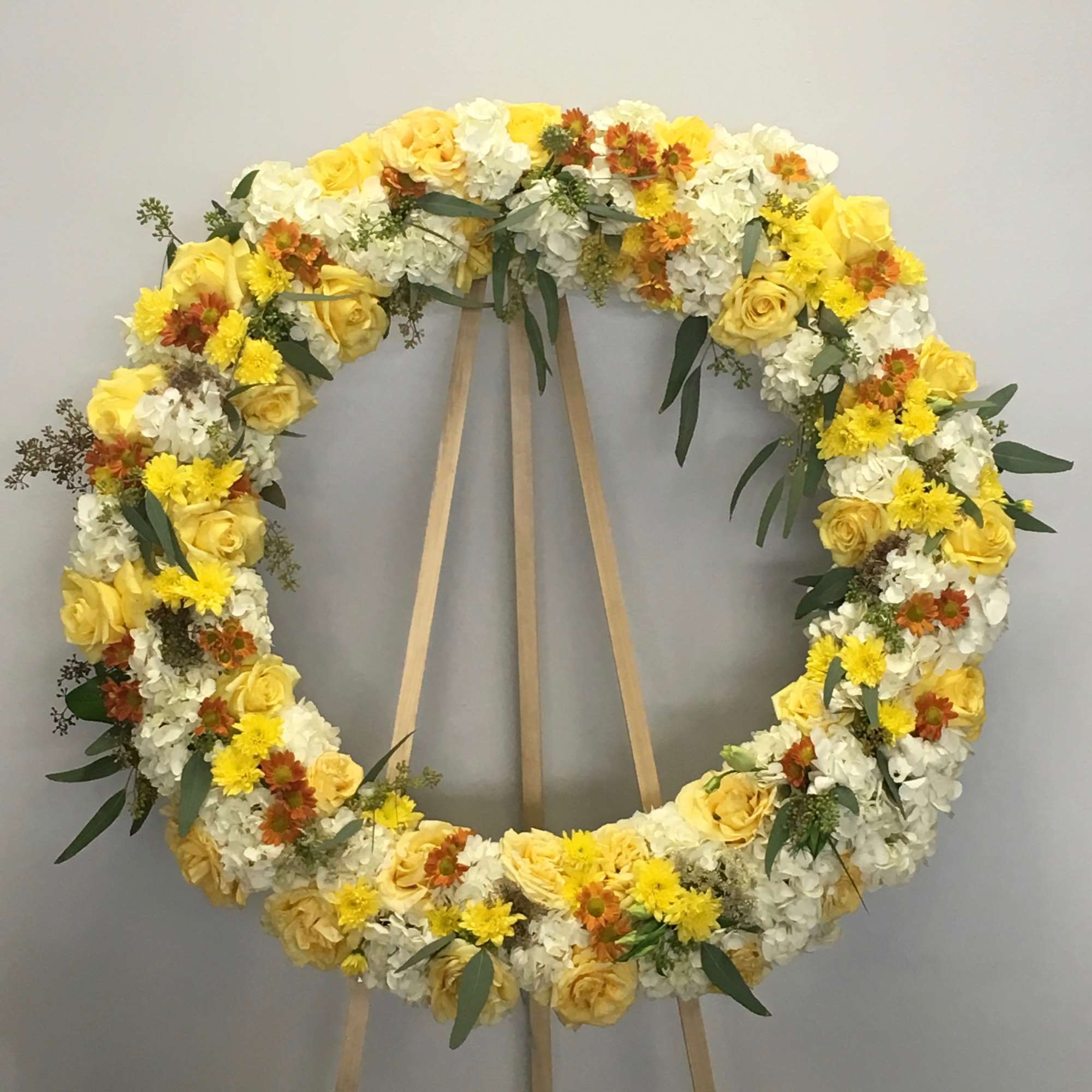 This wreath includes a bright mix of roses, hydrangeas, seasonal florals and