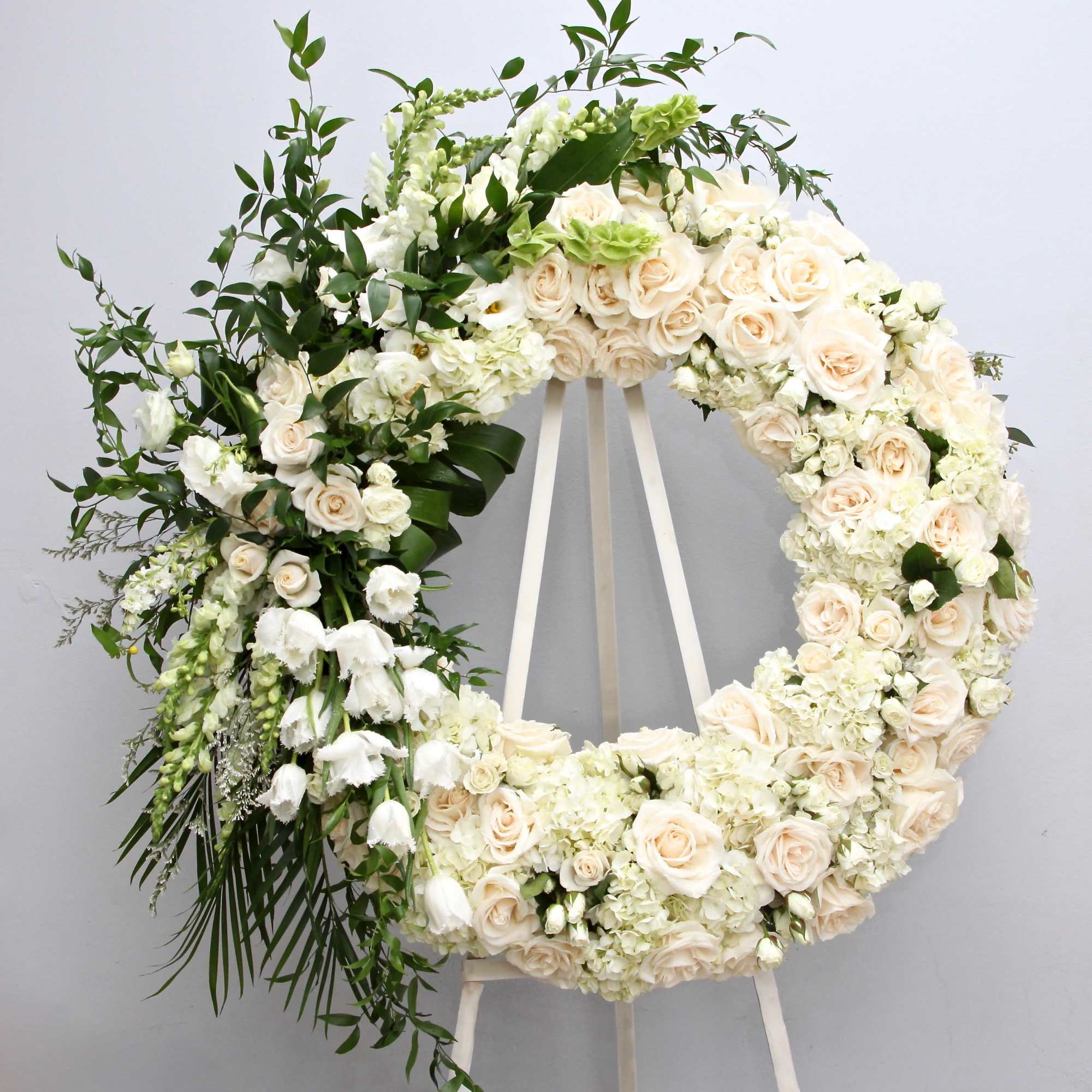 This sympathy wreath is elegantly designed with white roses, lilies, and orchids.

We