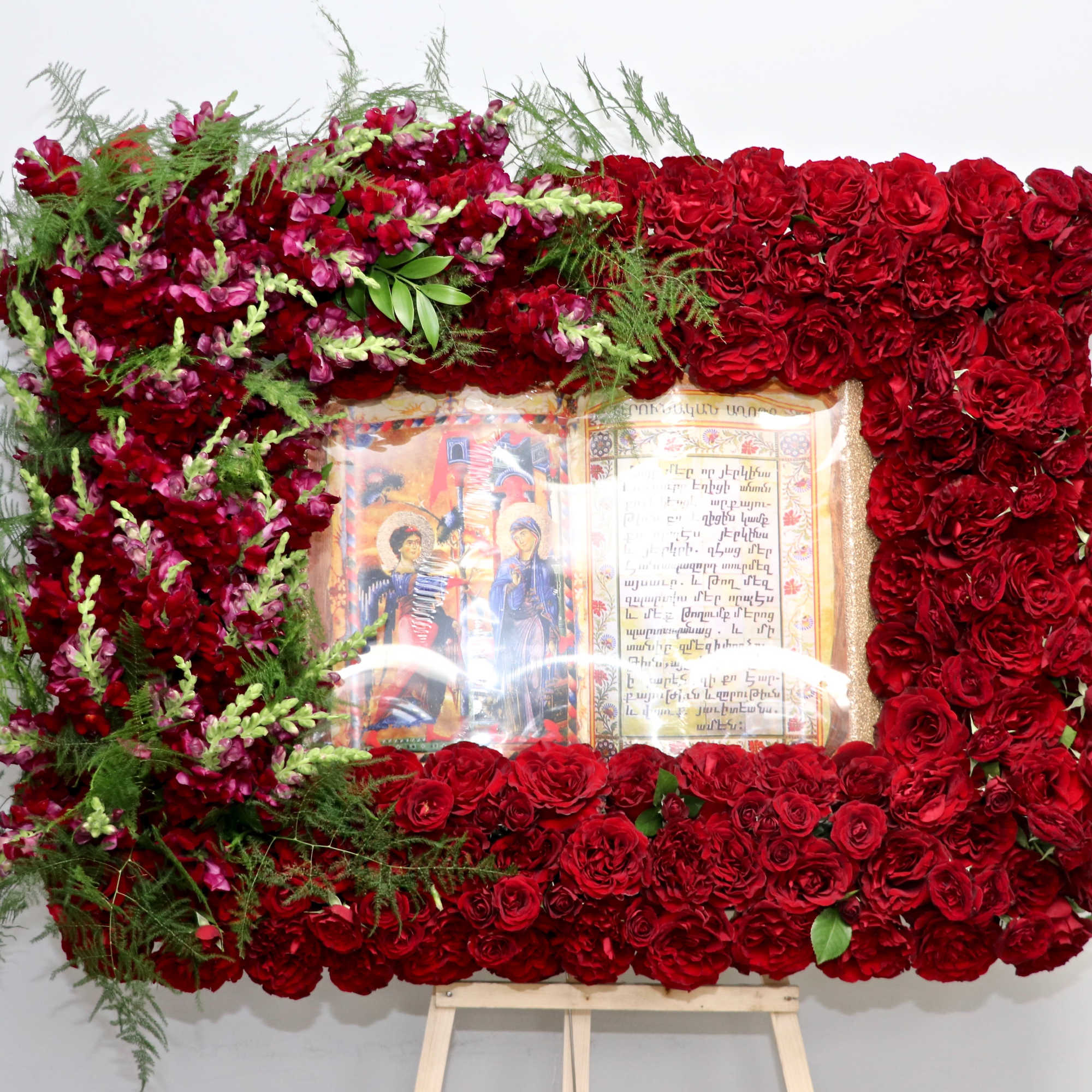 This frame includes a mix of roses and seasonal greens. Frames are