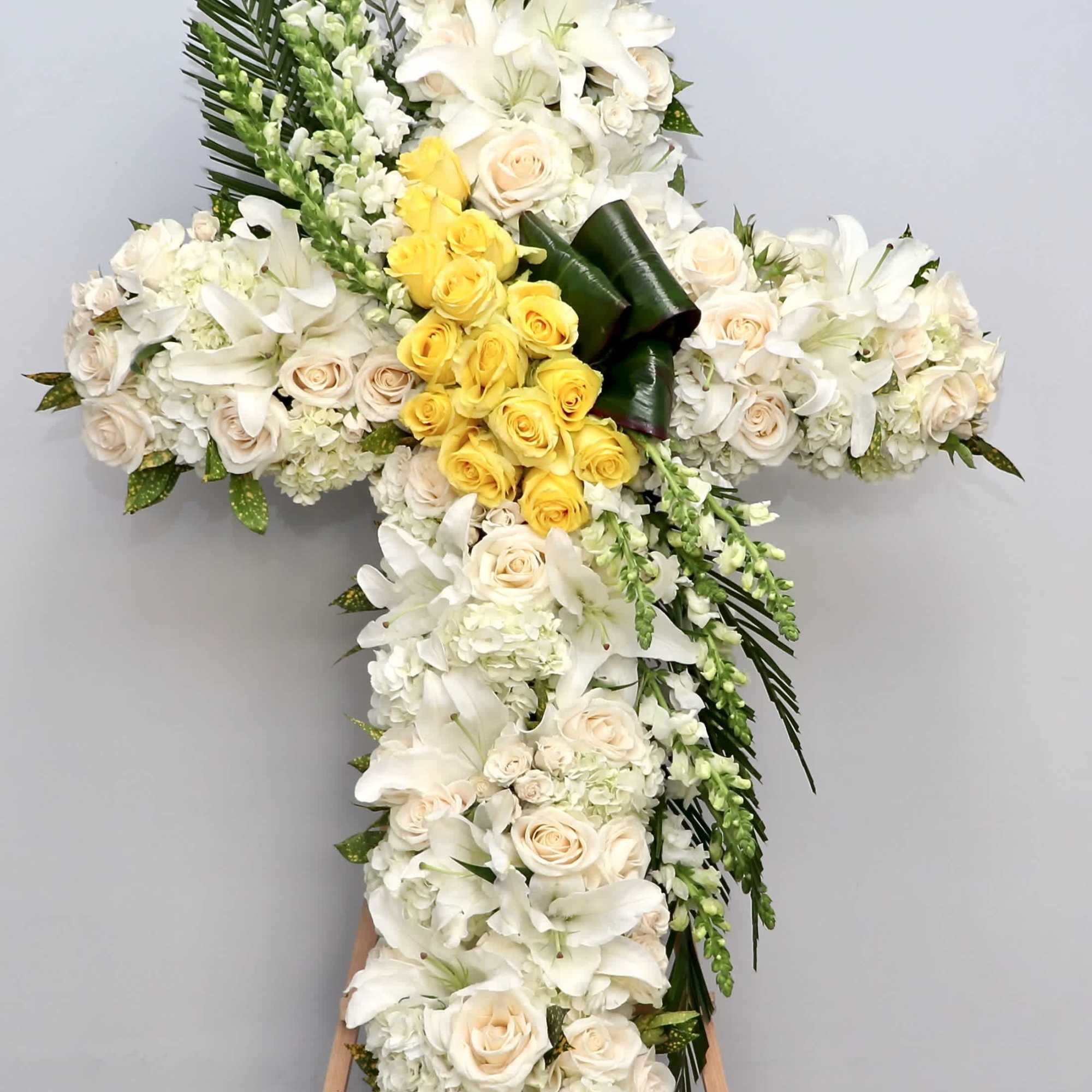This sympathy cross includes a center of yellow roses, hydrangeas, lilies, and