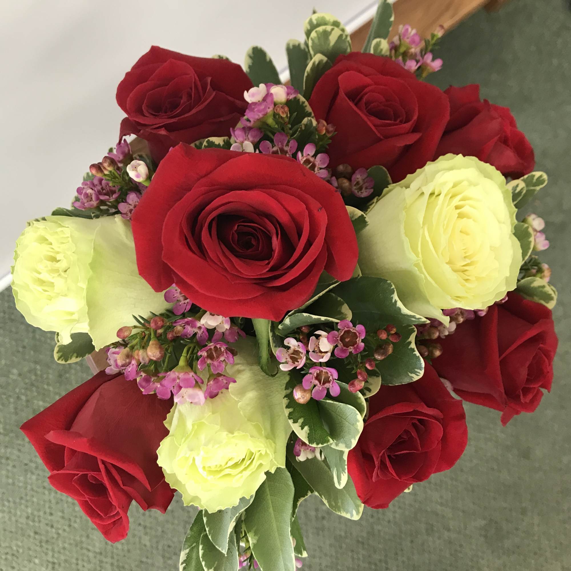 A graceful bouquet of 10 red and white roses with waxflower (or