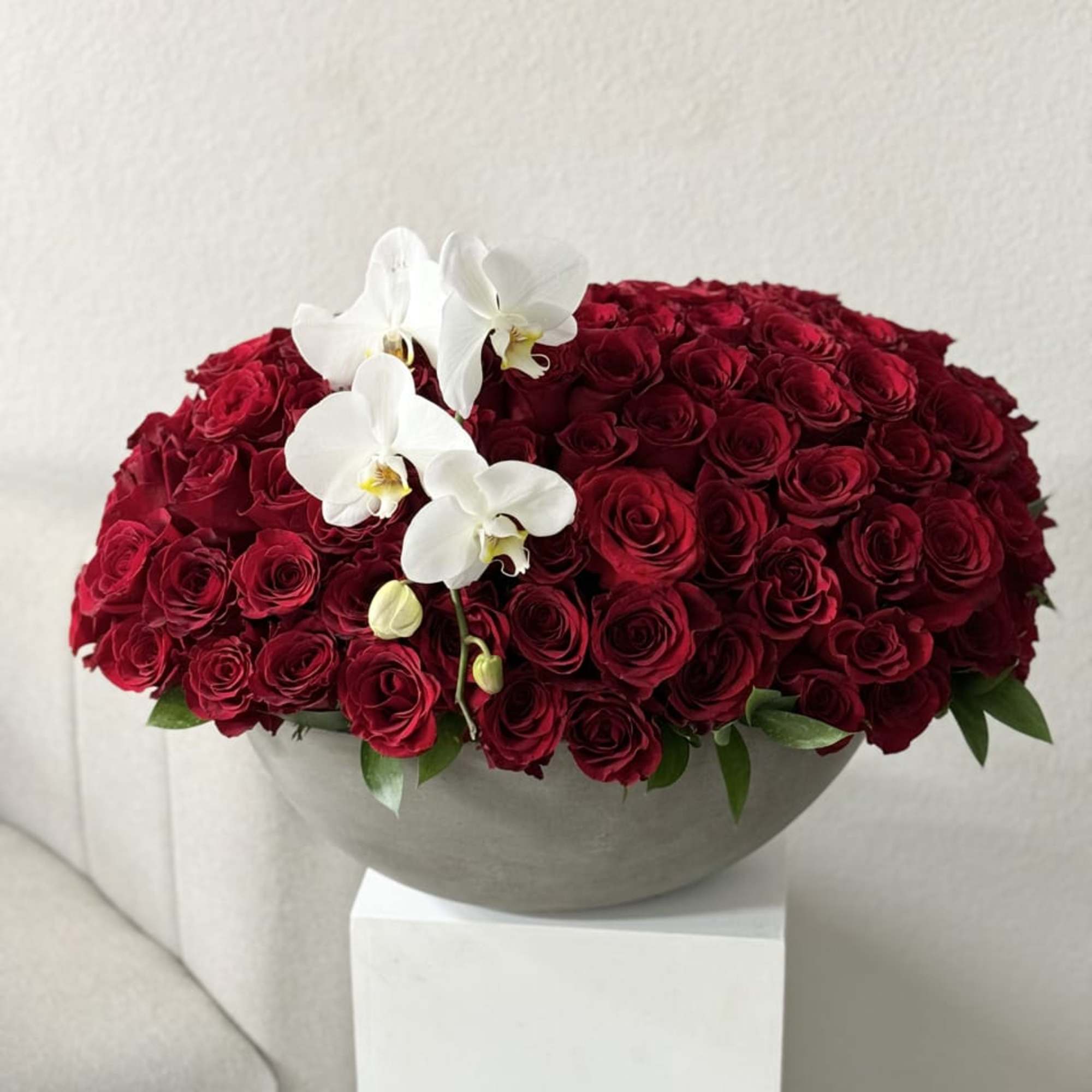 An opulent bouquet of 100 radiant red roses, beautifully arranged in a