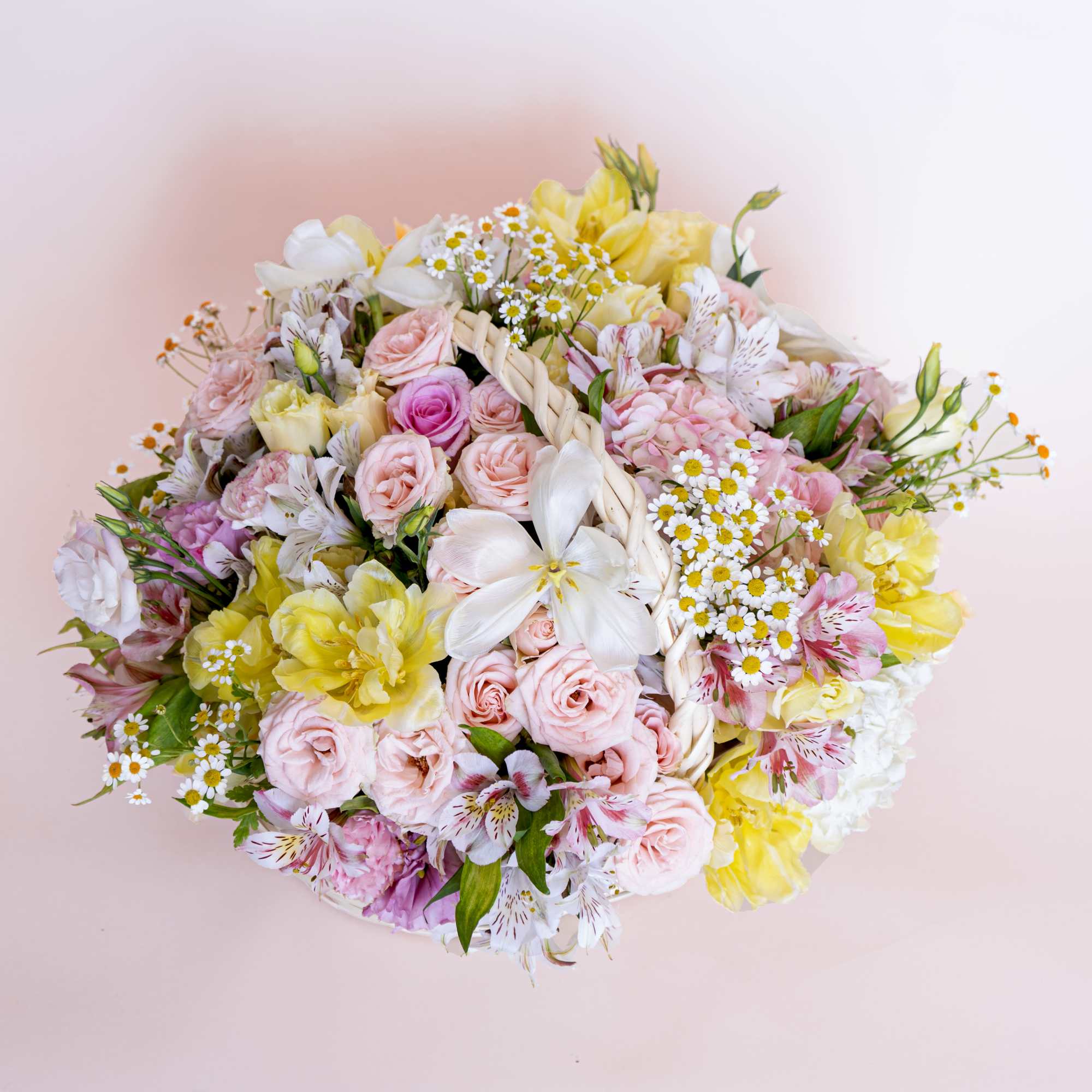 Bright-yellow tulips, chamomiles and light pink spray roses awaken the senses with