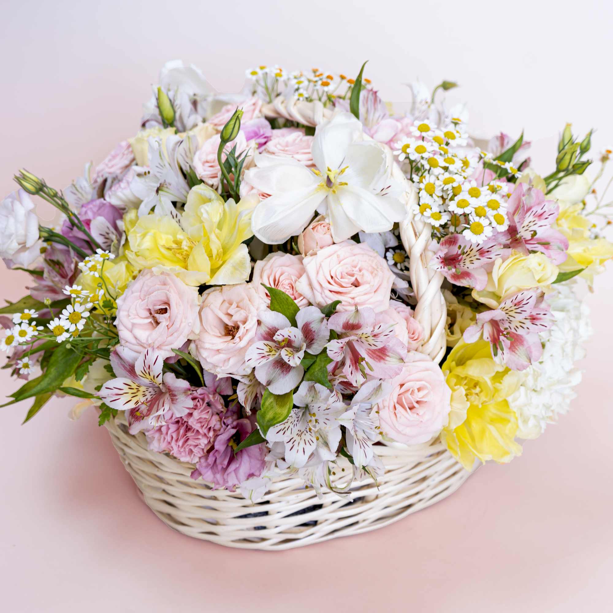 Bright-yellow tulips, chamomiles and light pink spray roses awaken the senses with