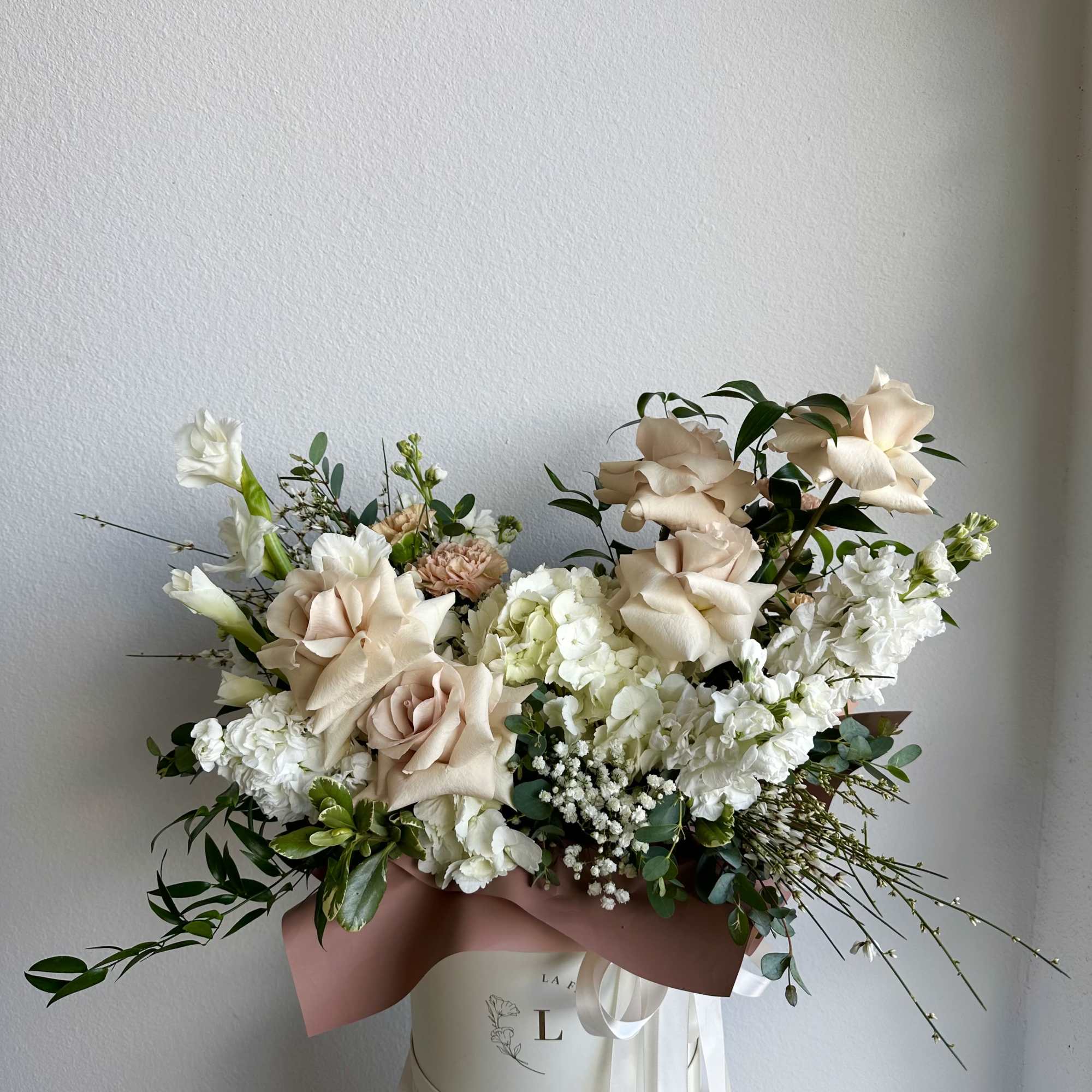 This beautiful arrangement is filled with beige roses, hydrangeas, carnations and greens