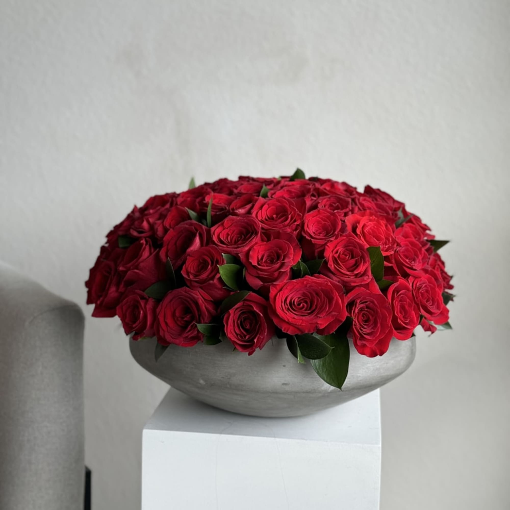 75 red roses arranged in a chic concrete vase, a striking fusion