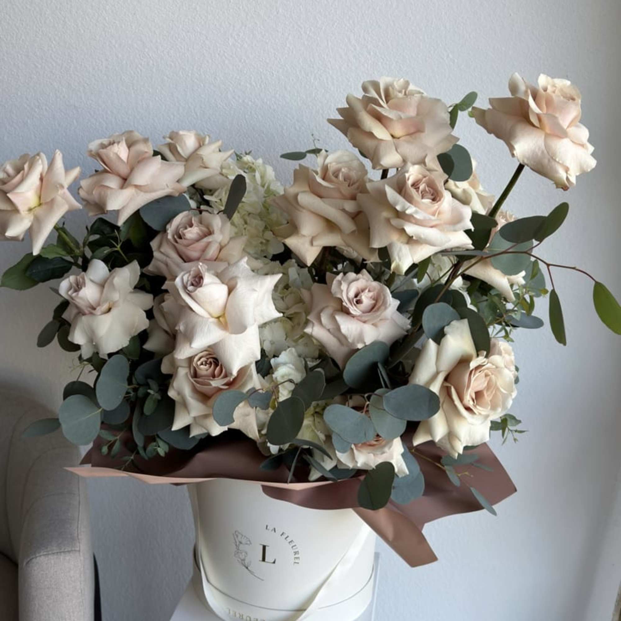 This beautiful arrangement is filled with beige color roses and greens to