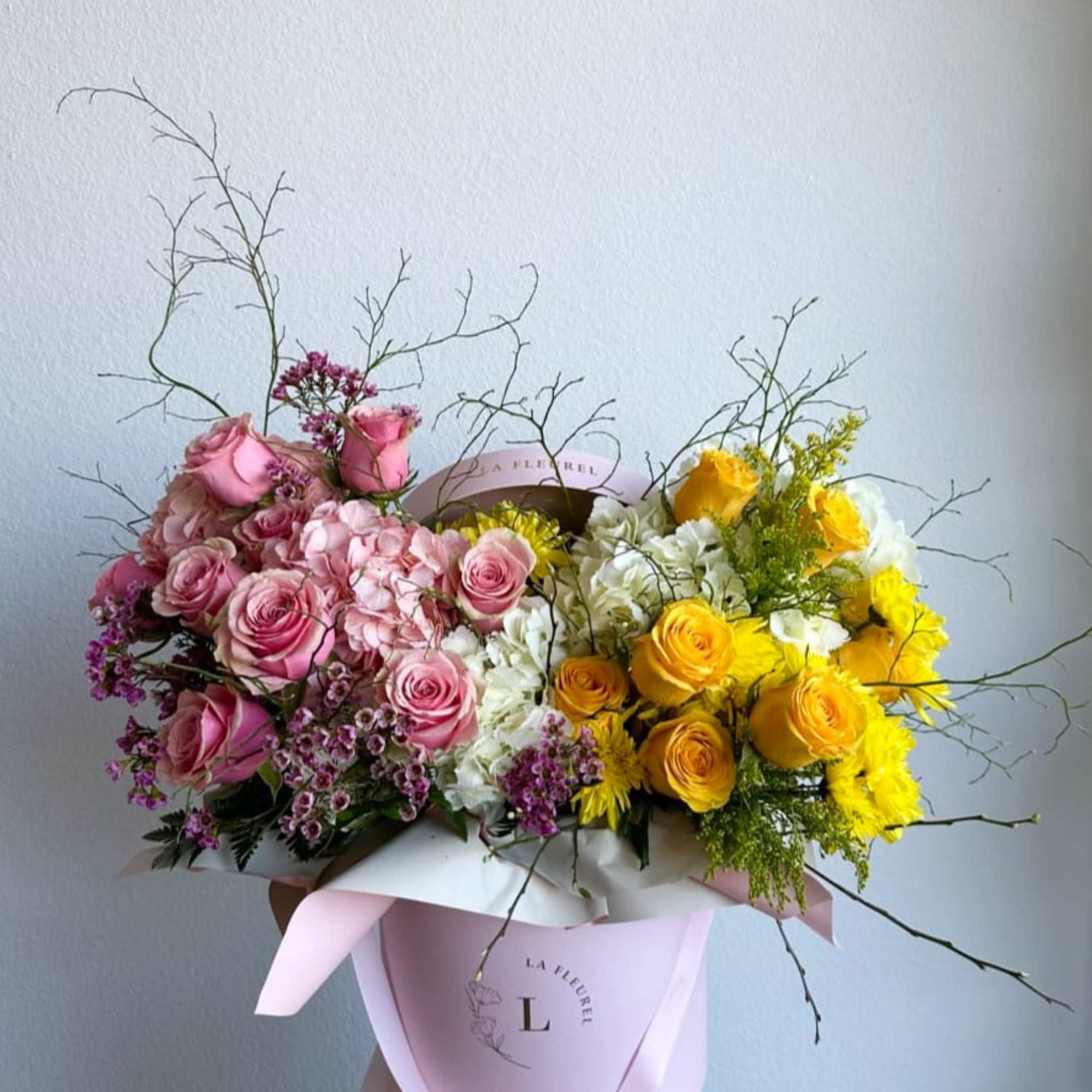 This beautiful arrangement is filled with yellow and pink roses, hydrangeas, and